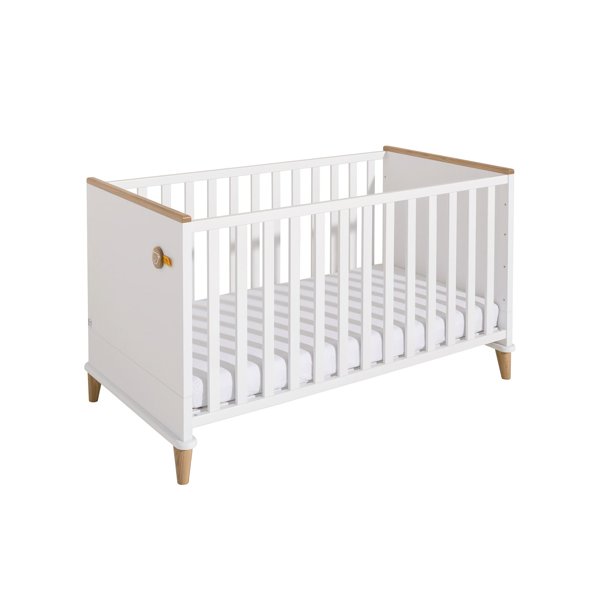 White baby crib with wooden legs and slatted sides, mattress inside.