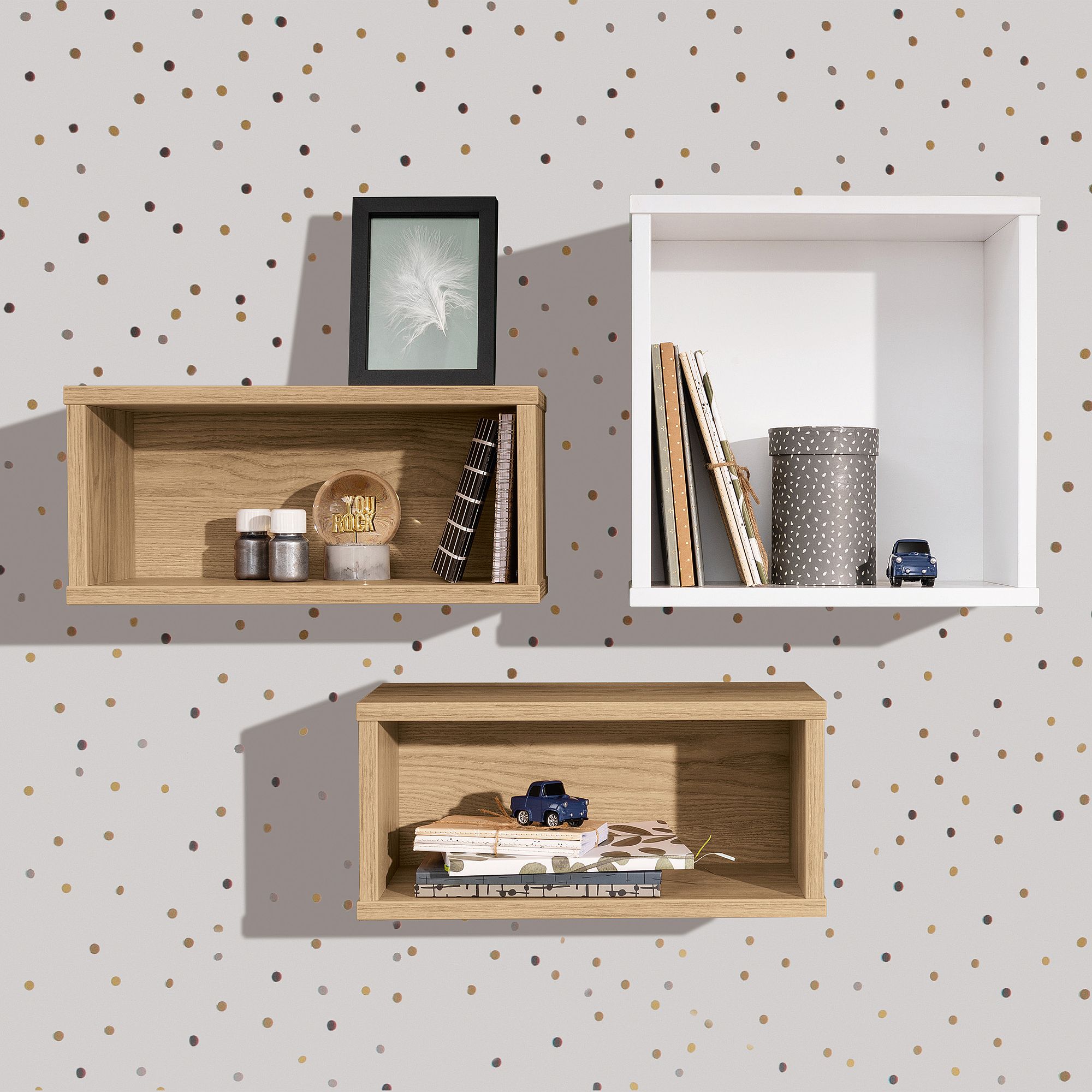Wandregal  Wandbox  quadratisch in Kreideweiß Drei Kistenregale mit Büchern, Dekoration und Spielzeugautos vor einer gepunkteten Wand.