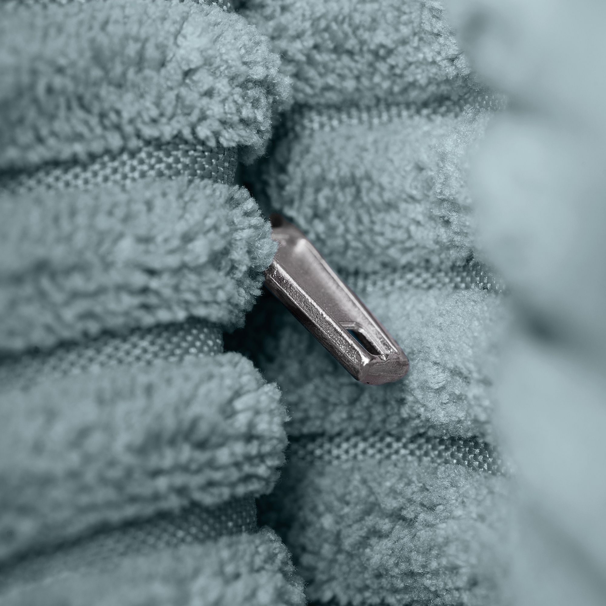 Nahaufnahme eines Reißverschlusses zwischen weichem, hellblauem, strukturiertem Stoff.