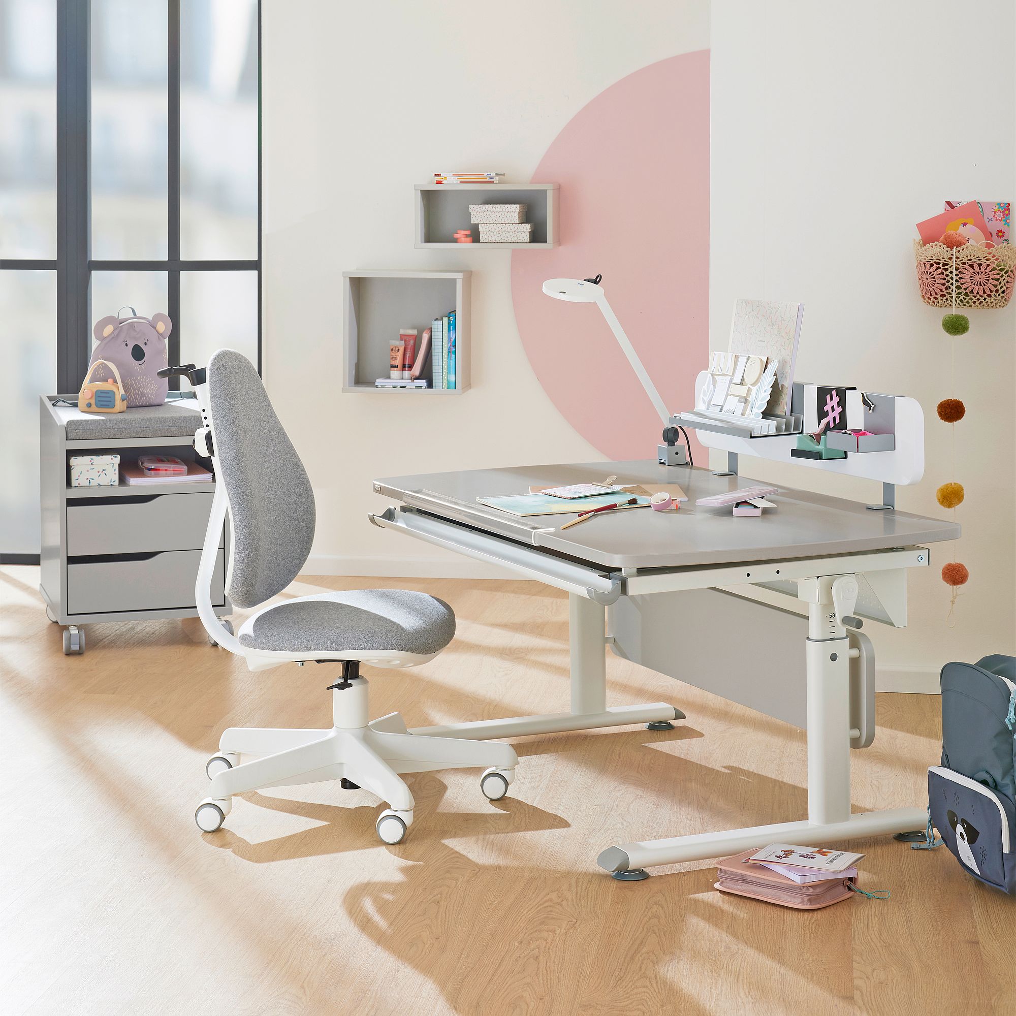 Rollcontainer  mit 2 Schubladen in Kieselgrau Moderner Schreibtisch mit einem grauen Stuhl, Büchern und Schreibwaren in einem hellen Raum.