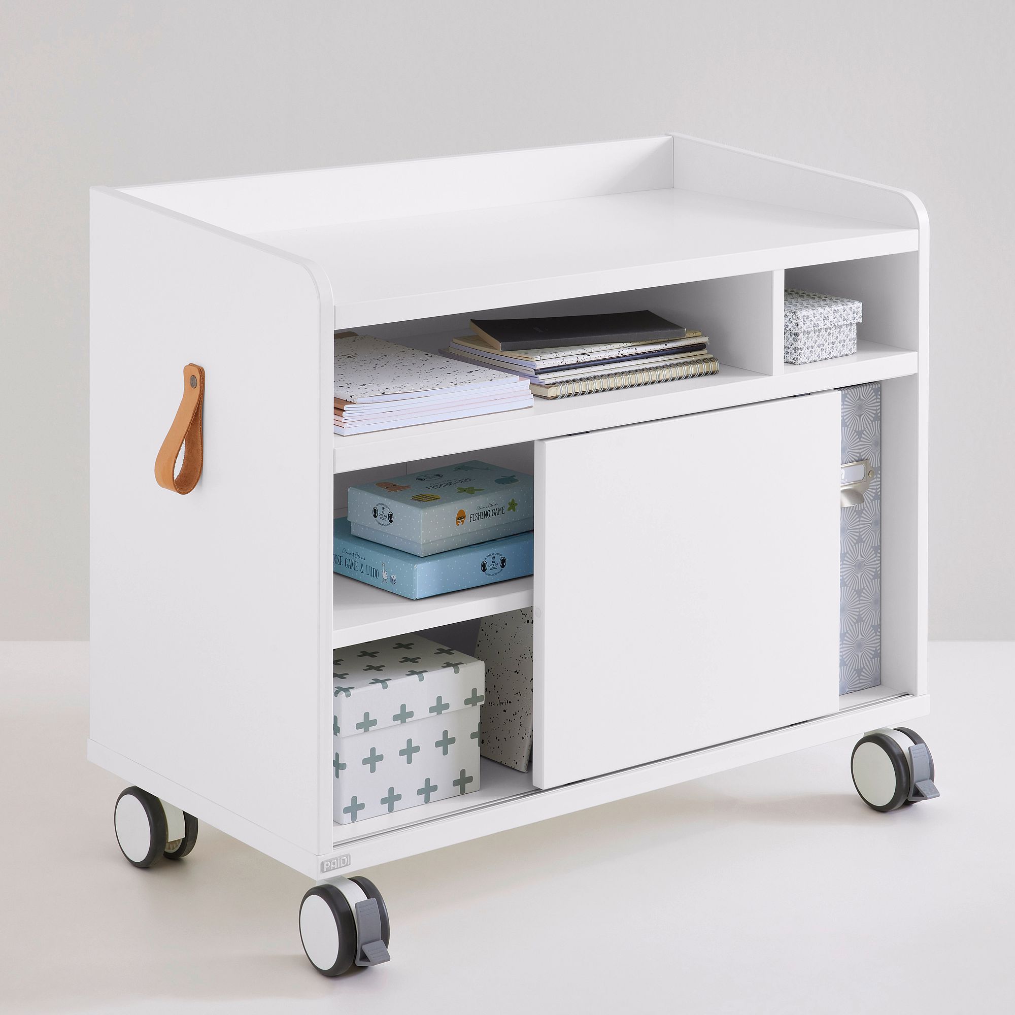 White rolling storage cart with shelves, books, boxes, and a leather handle.