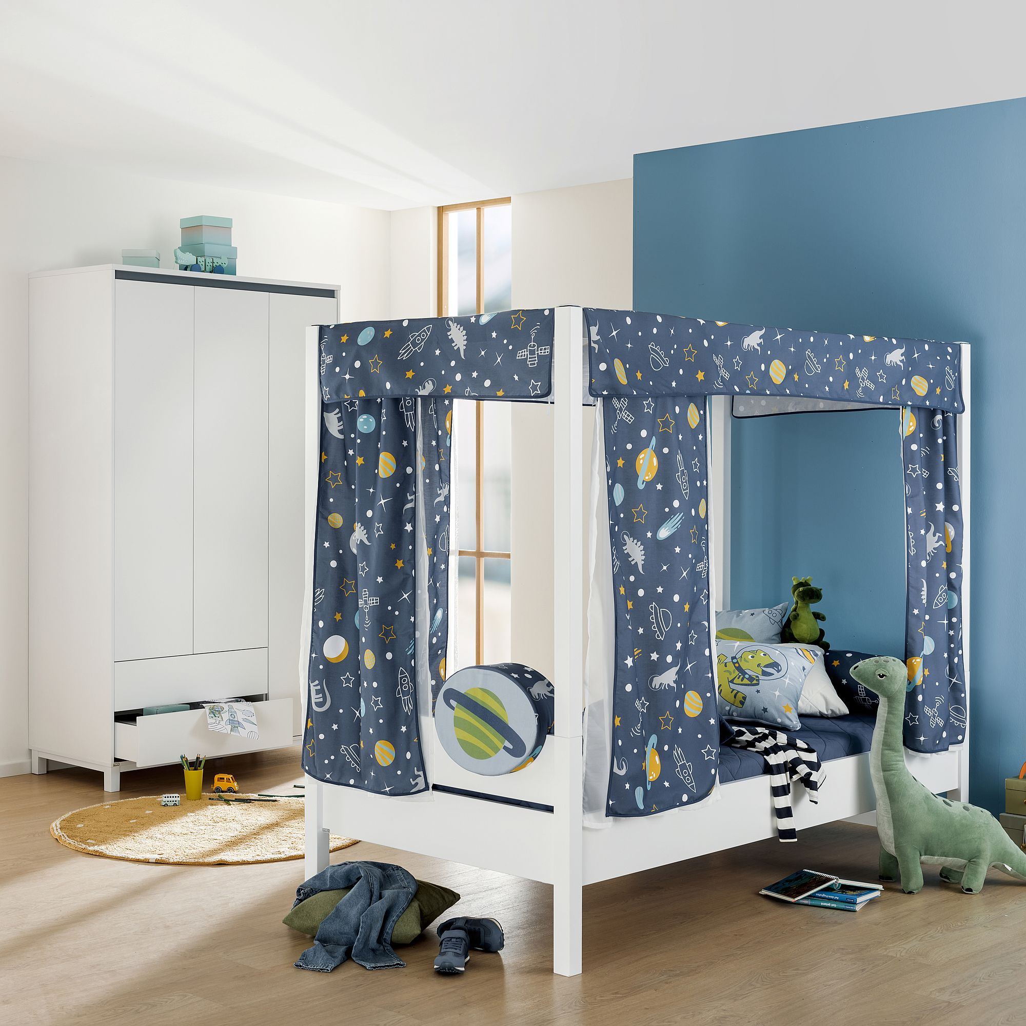 Kinderzimmer mit einem Himmelbett im Weltraum-Design und Dinosaurier-Spielzeug.