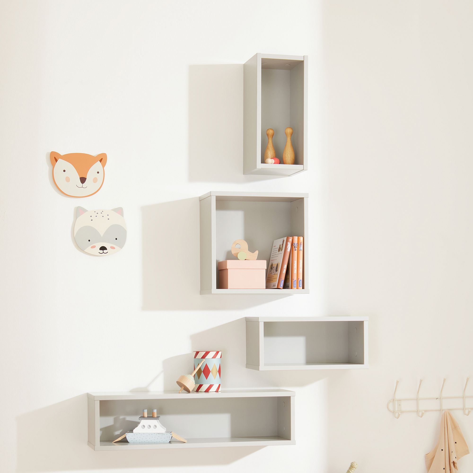 Four gray wall shelves with toys, books, and animal face wall decorations.