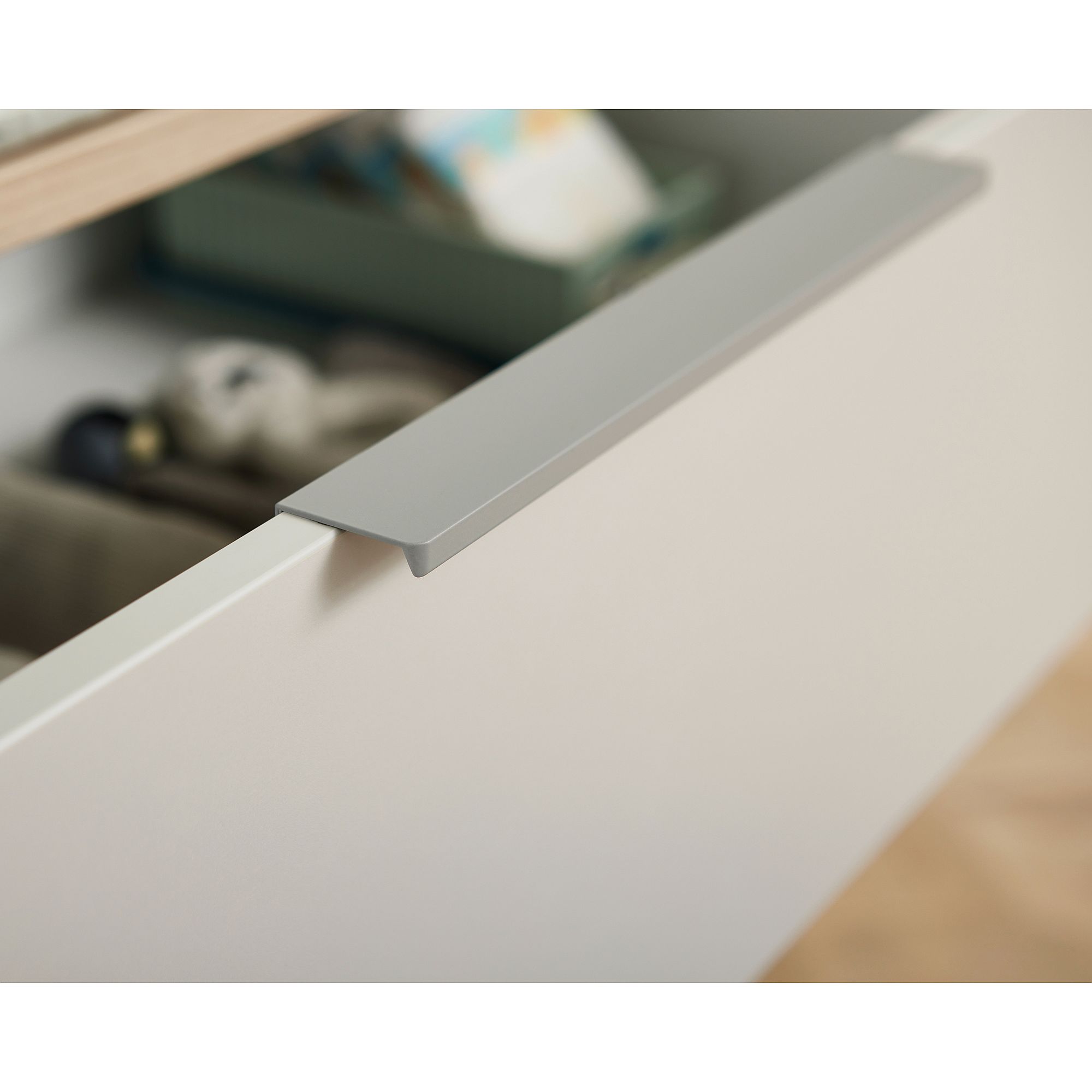 A close-up of a partially open drawer with a simple, modern silver handle.