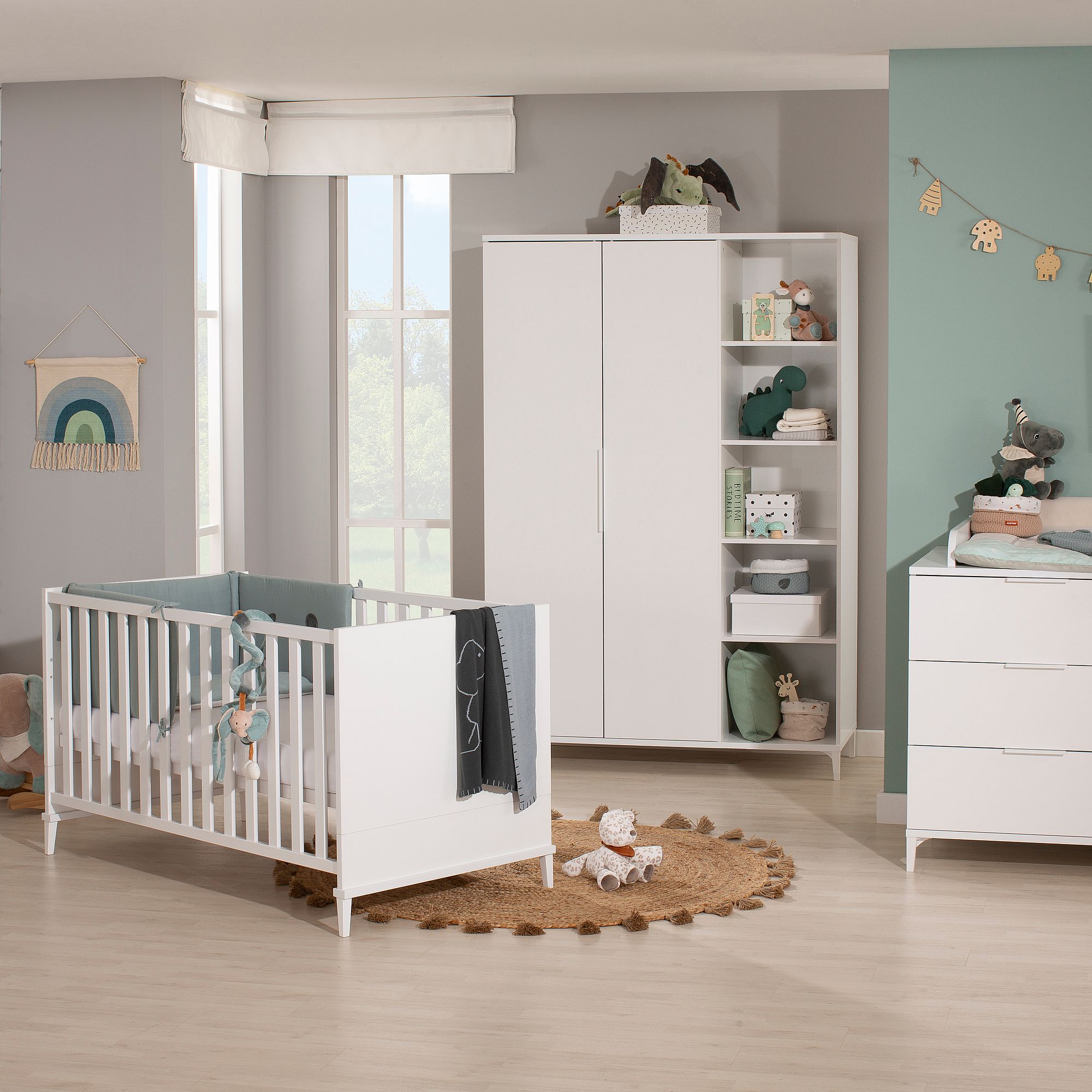 Modernes Kinderzimmer mit weißem Kinderbett, Kleiderschrank und Regalen in sanften Pastelltönen.