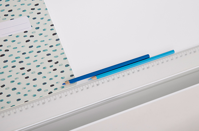 A patterned notebook, two blue pencils, and a white ruler are arranged neatly on a white surface.