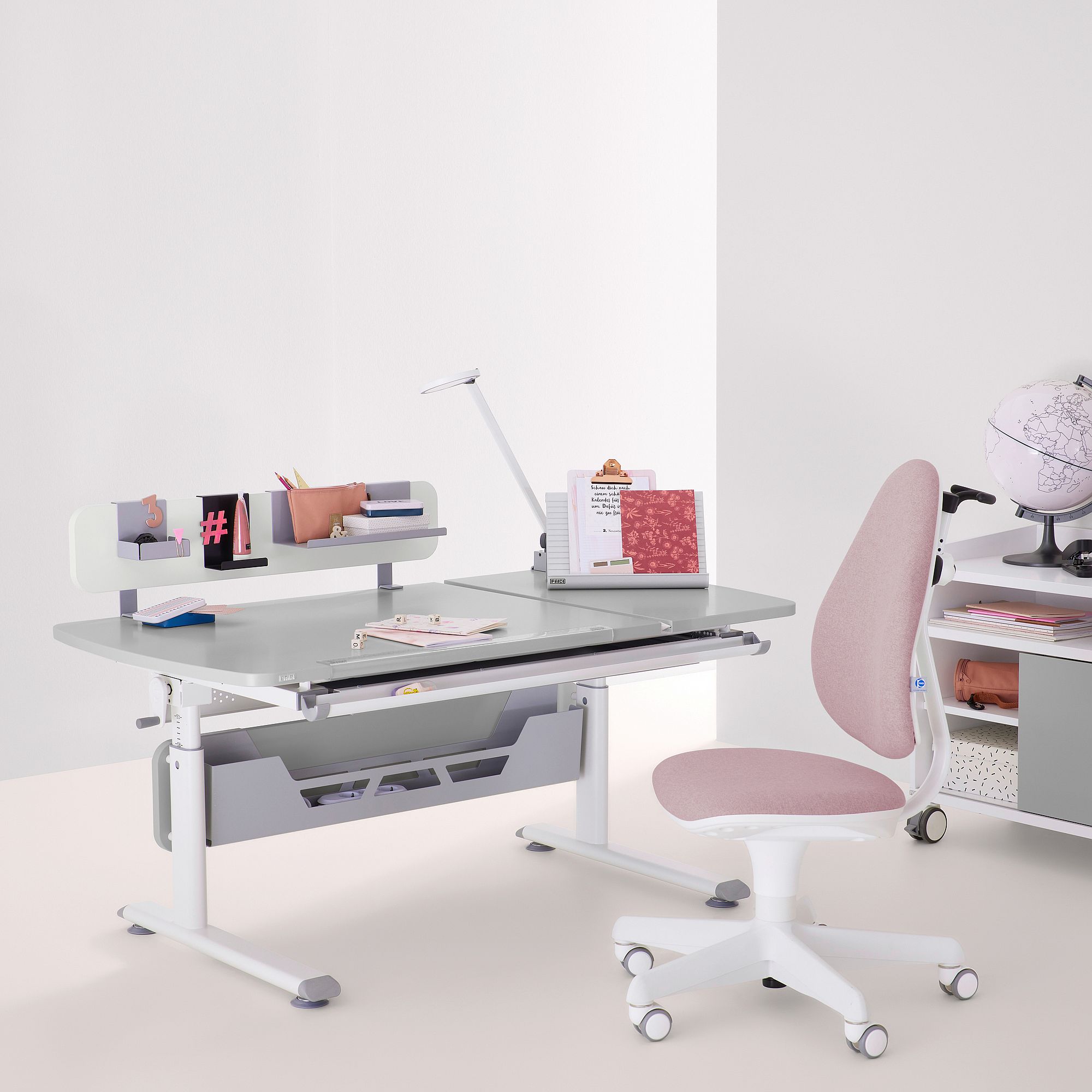 Moderner Arbeitstisch mit Büchern, Lampe und rosa Stuhl in einem minimalistisch eingerichteten Raum.