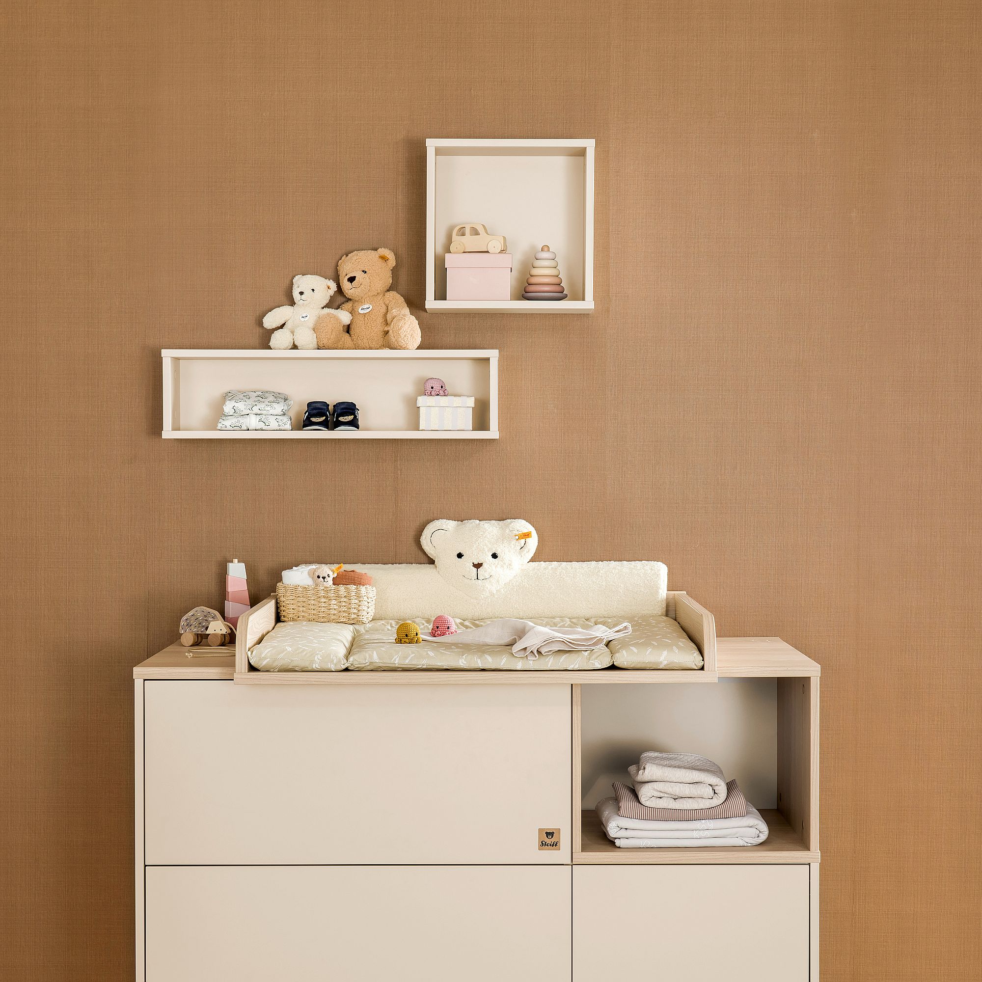 Wandregal  Wandbox  quadratisch in Cashmere-Beige Neutrales Kinderzimmer mit Spielzeug, einem Wickeltisch und Babyzubehör vor einer braunen Wand.
