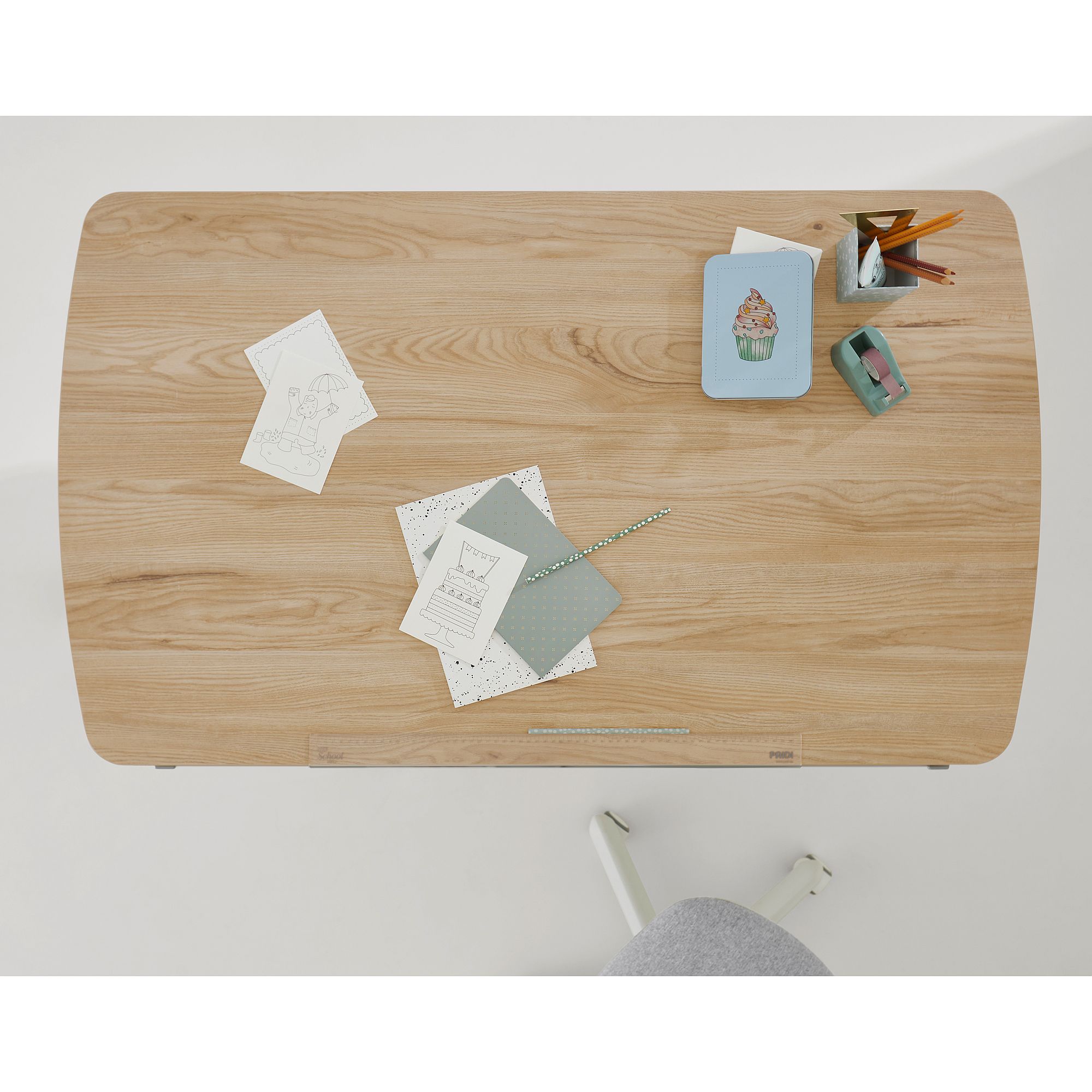 Schülerschreibtisch Diego Curved 120 x 70 cm in Eiche Montana Draufsicht auf einen hölzernen Schreibtisch mit Papieren, Bleistiften, einem Notizbuch und einem Stuhl.