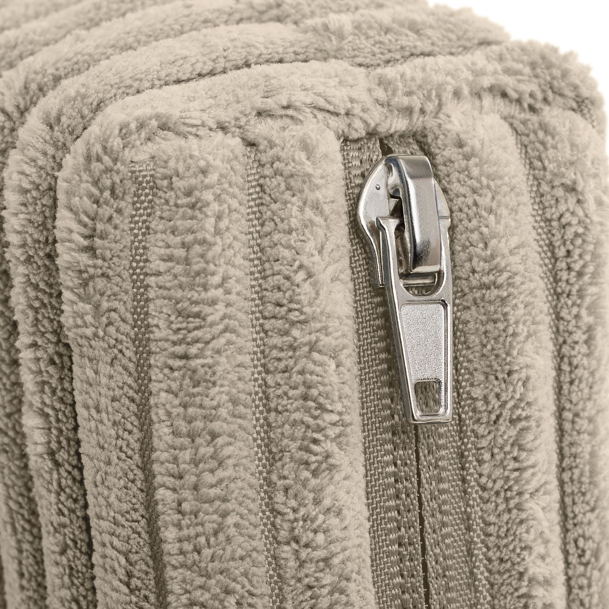 Nahaufnahme eines silbernen Reißverschlusses auf einer weichen, strukturierten beigen Stoffoberfläche.
