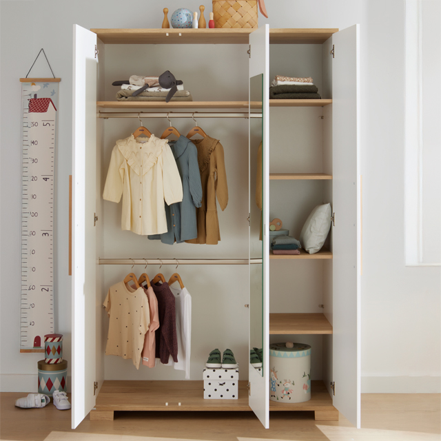 1106_PAIDI_Shop_Start_Feed_Kleiderschrnke-ID1697558_5191af14-a928-041f-80fd-a9a020a9f209.jpg Offener weißer Kleiderschrank mit Kinderkleidung, Schuhen und gefalteten Gegenständen, ordentlich angeordnet.