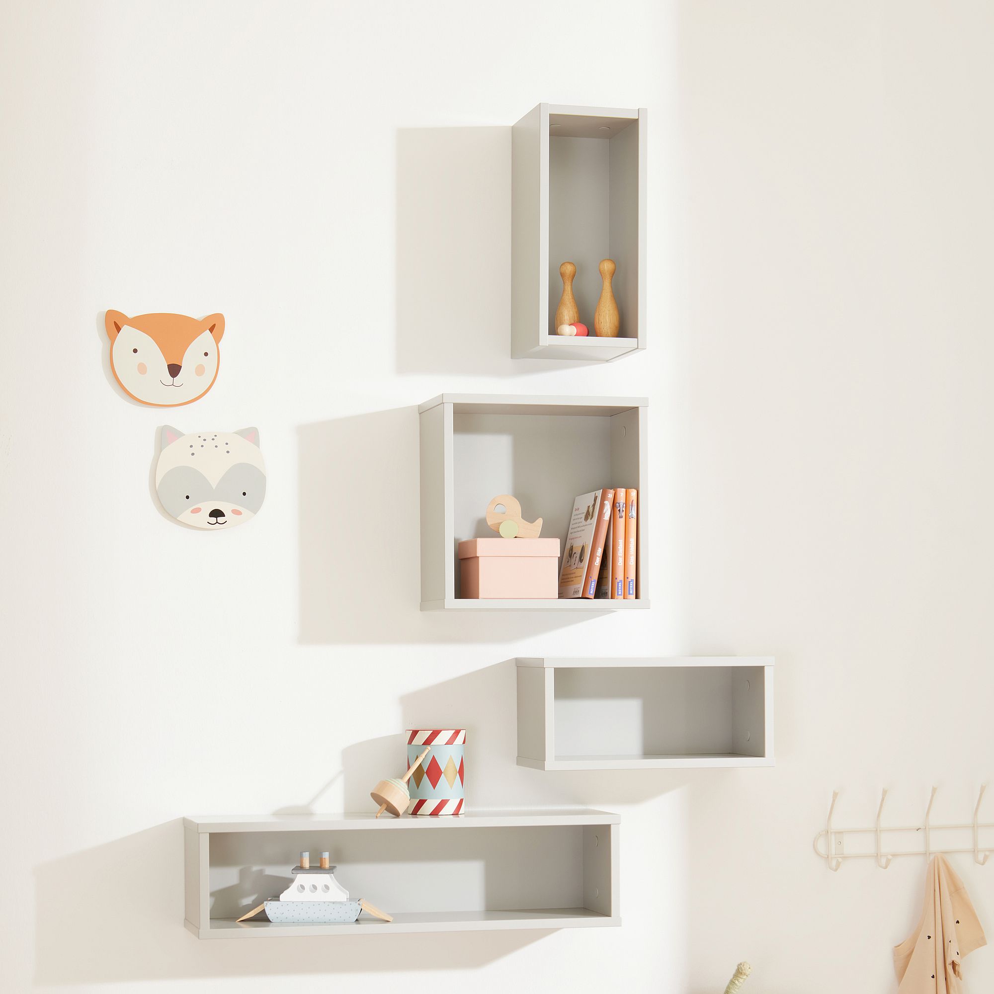 Wandregal  Wandbox  quadratisch in Kreideweiß Vier graue Wandregale mit Spielzeug, Büchern und Wanddekoration mit Tiergesichtern darüber.