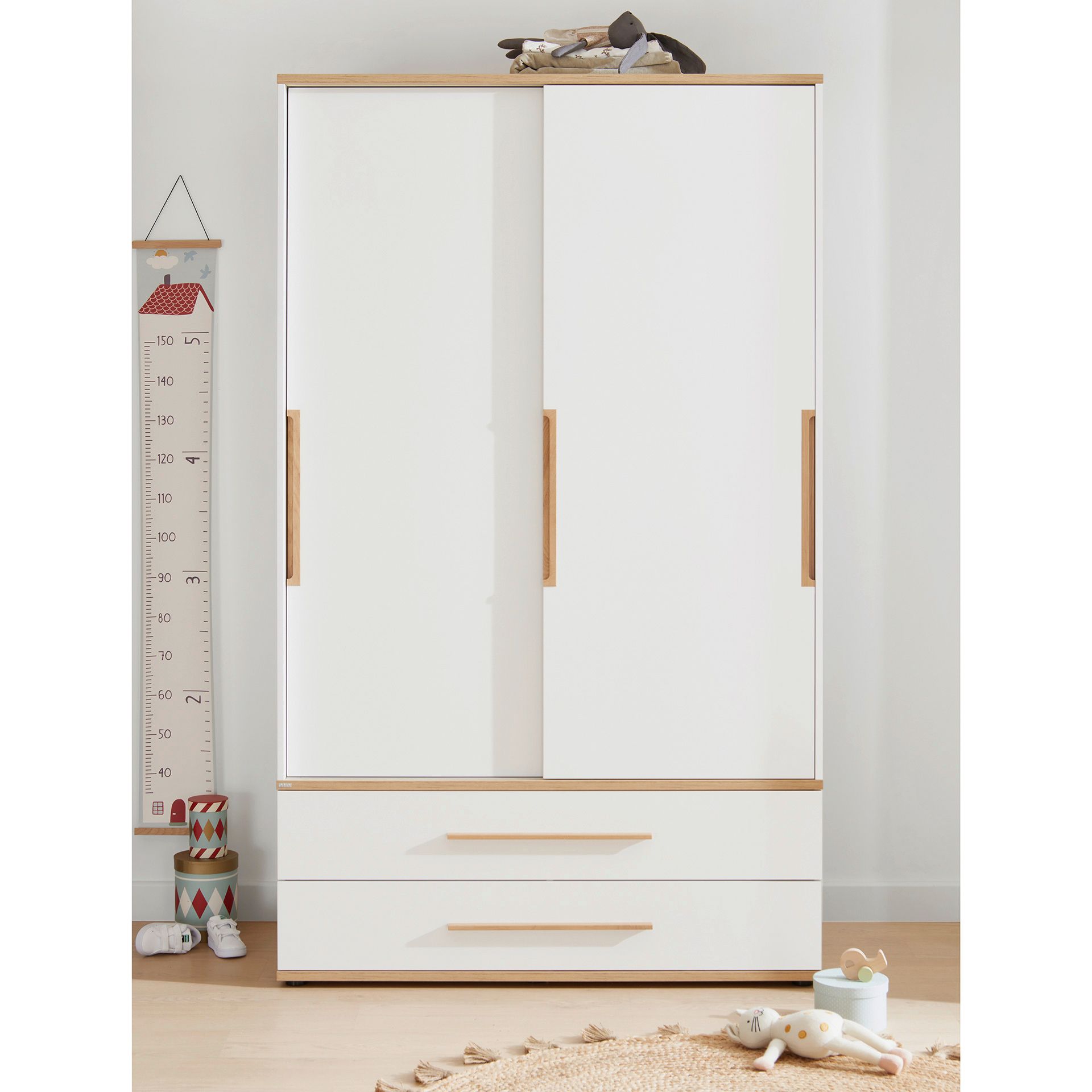 White wardrobe with sliding doors and drawers in a childrens room.