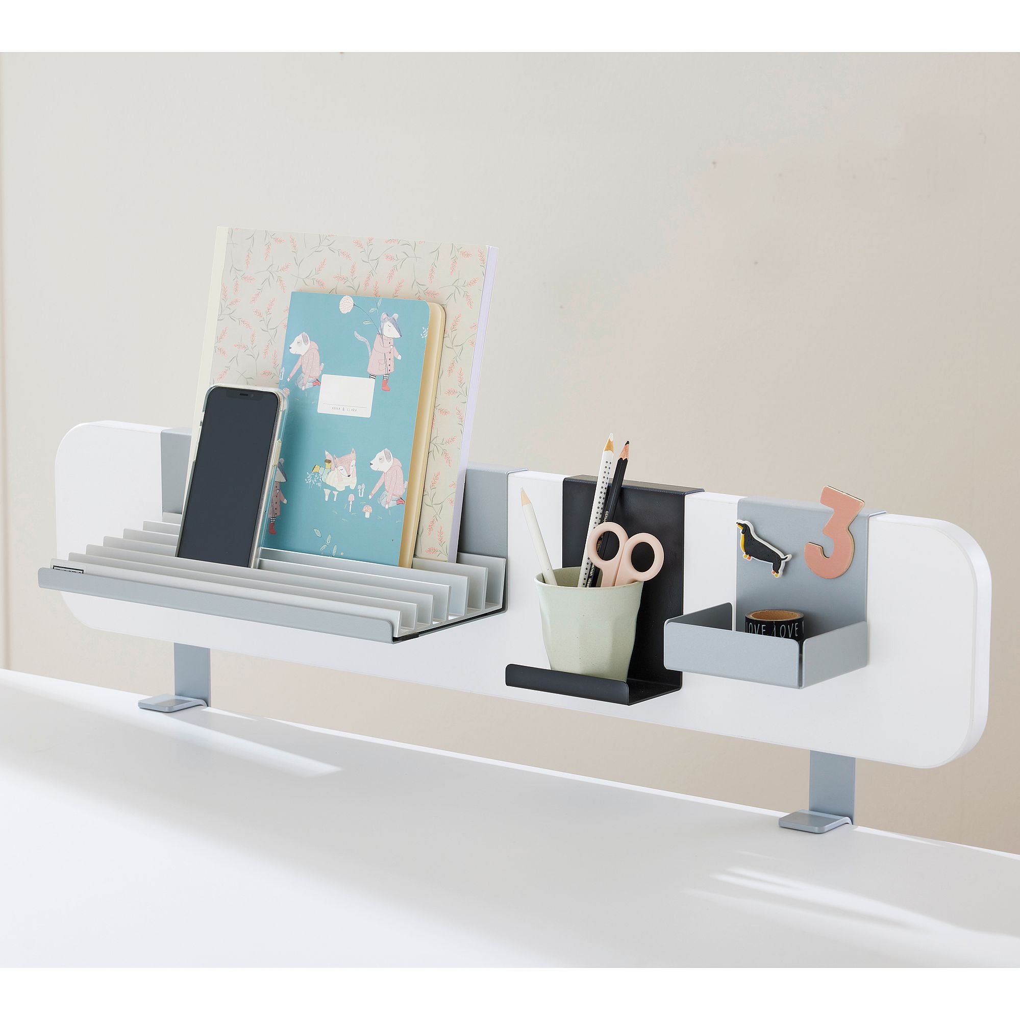White desk organizer holding folders, a phone, scissors, pens, and small items.