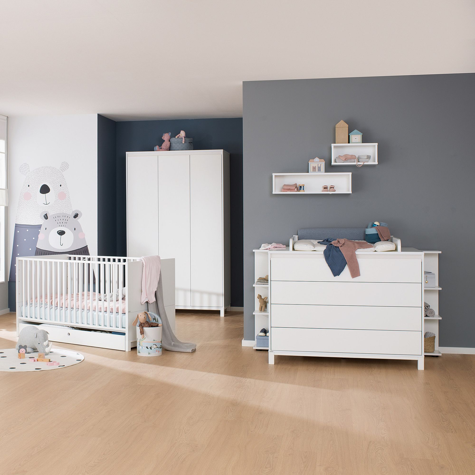 Modernes Kinderzimmer mit einem weißen Kinderbett, einer Kommode, einem Kleiderschrank und einer Bärenwandgestaltung.