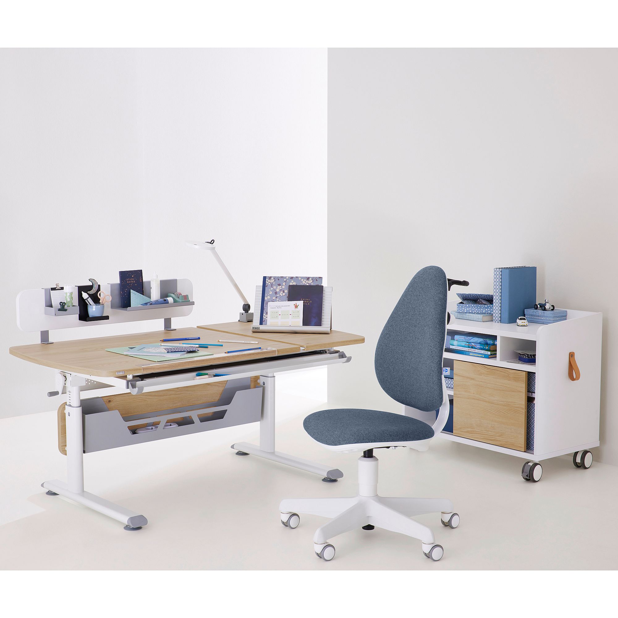 Schülerschreibtisch Diego GT Curved mit geteilter Platte 130 x 70 cm in Eiche-Montana Ein moderner Schreibtisch mit einem grauen Stuhl und einem weißen Rollcontainer.