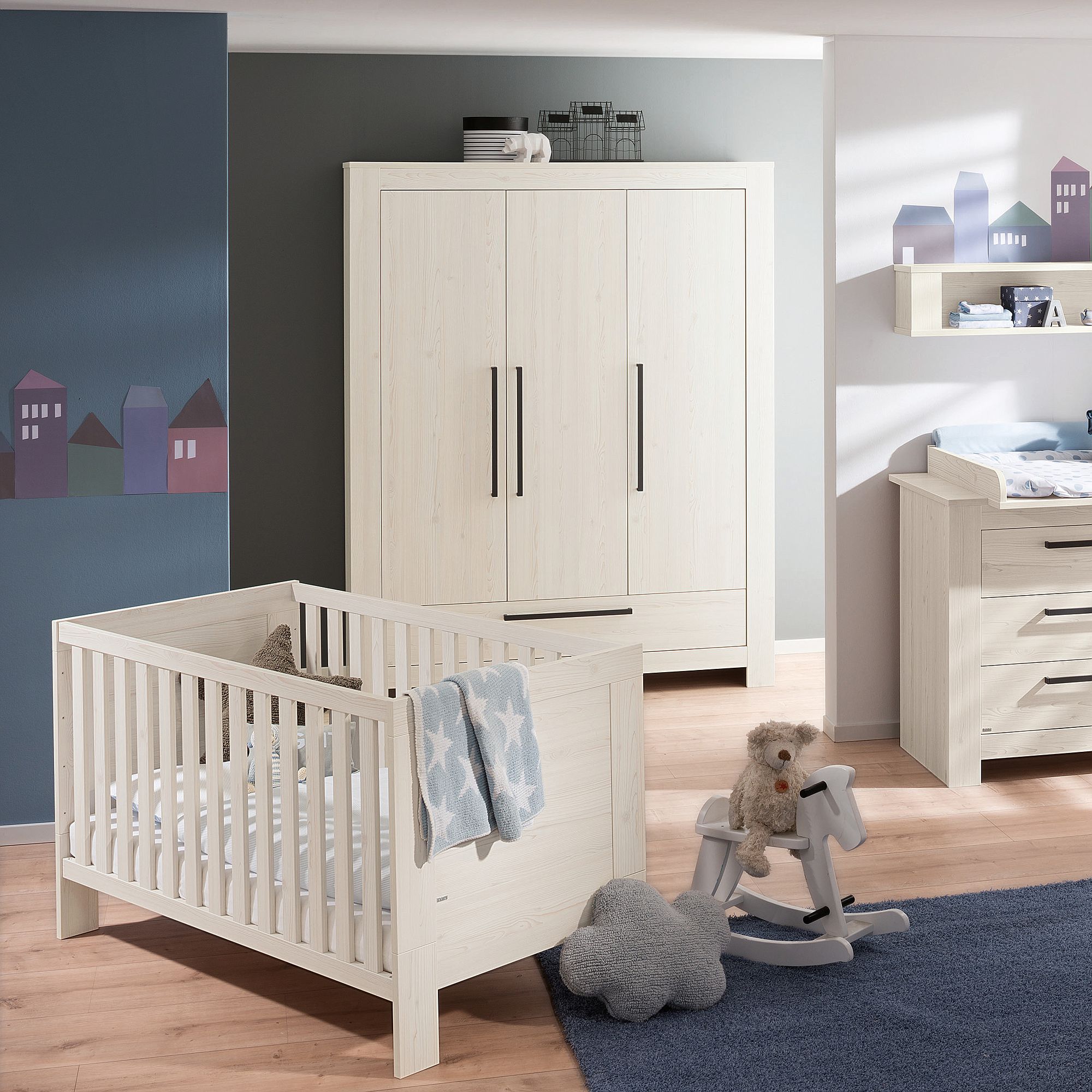 Modernes Kinderzimmer mit weißem Kinderbett, Kleiderschrank, Kommode und Plüschtieren auf dem Boden.