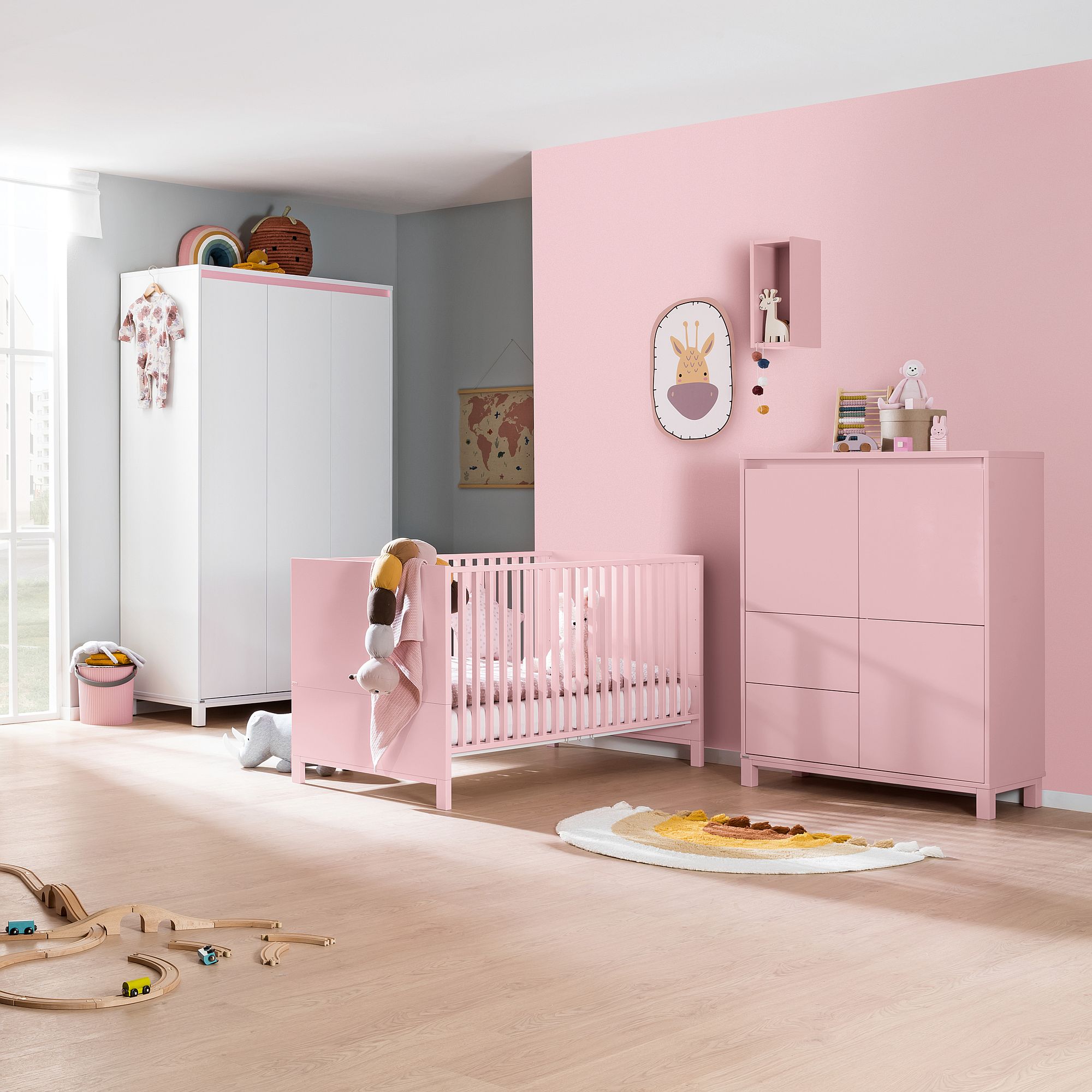 Modernes Kinderzimmer mit rosa Kinderbett, Kommode und Wand sowie Spielzeug und Dekoration.