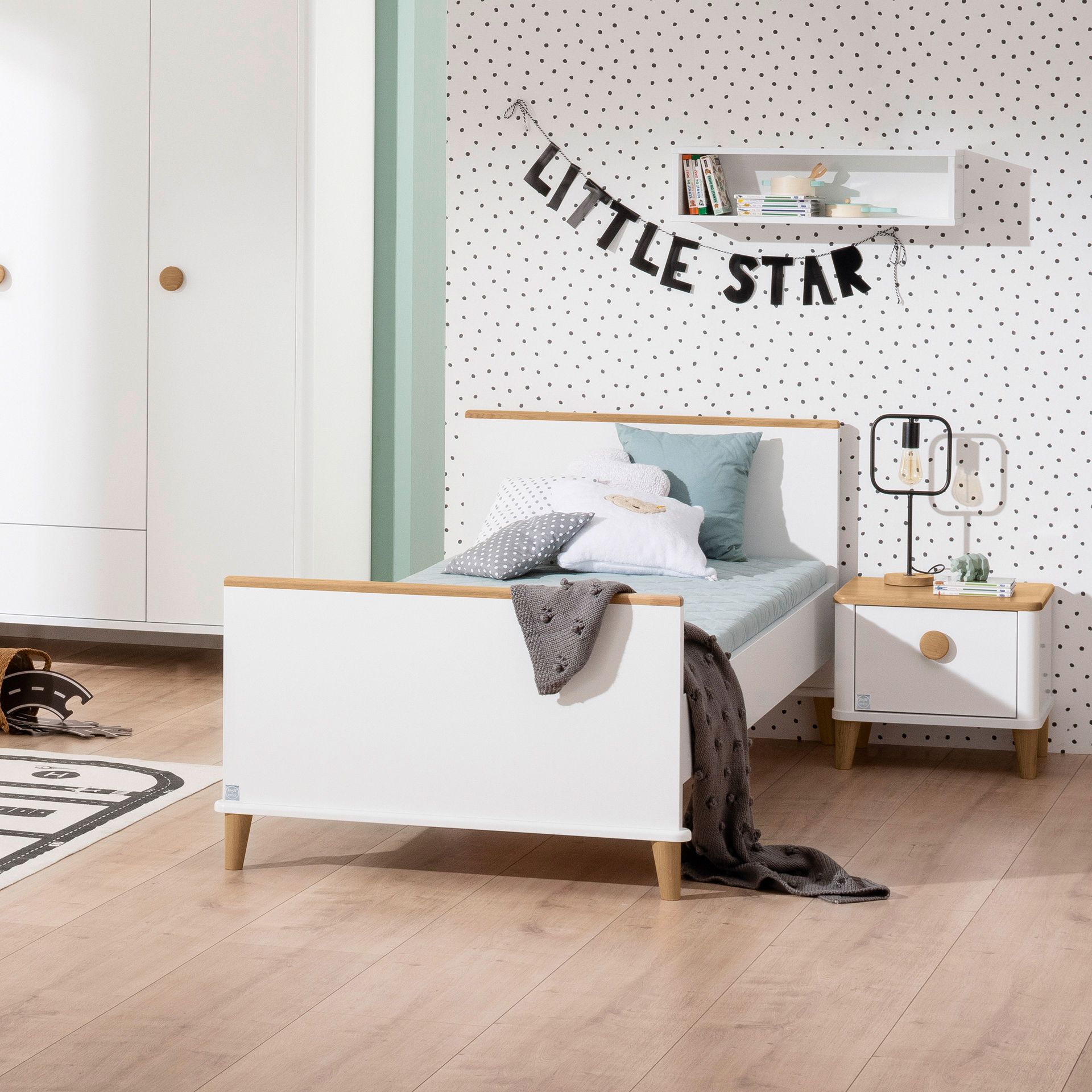 Minimalist kids’ bedroom with white bed, polka-dot wall, and “Little Star” banner.
