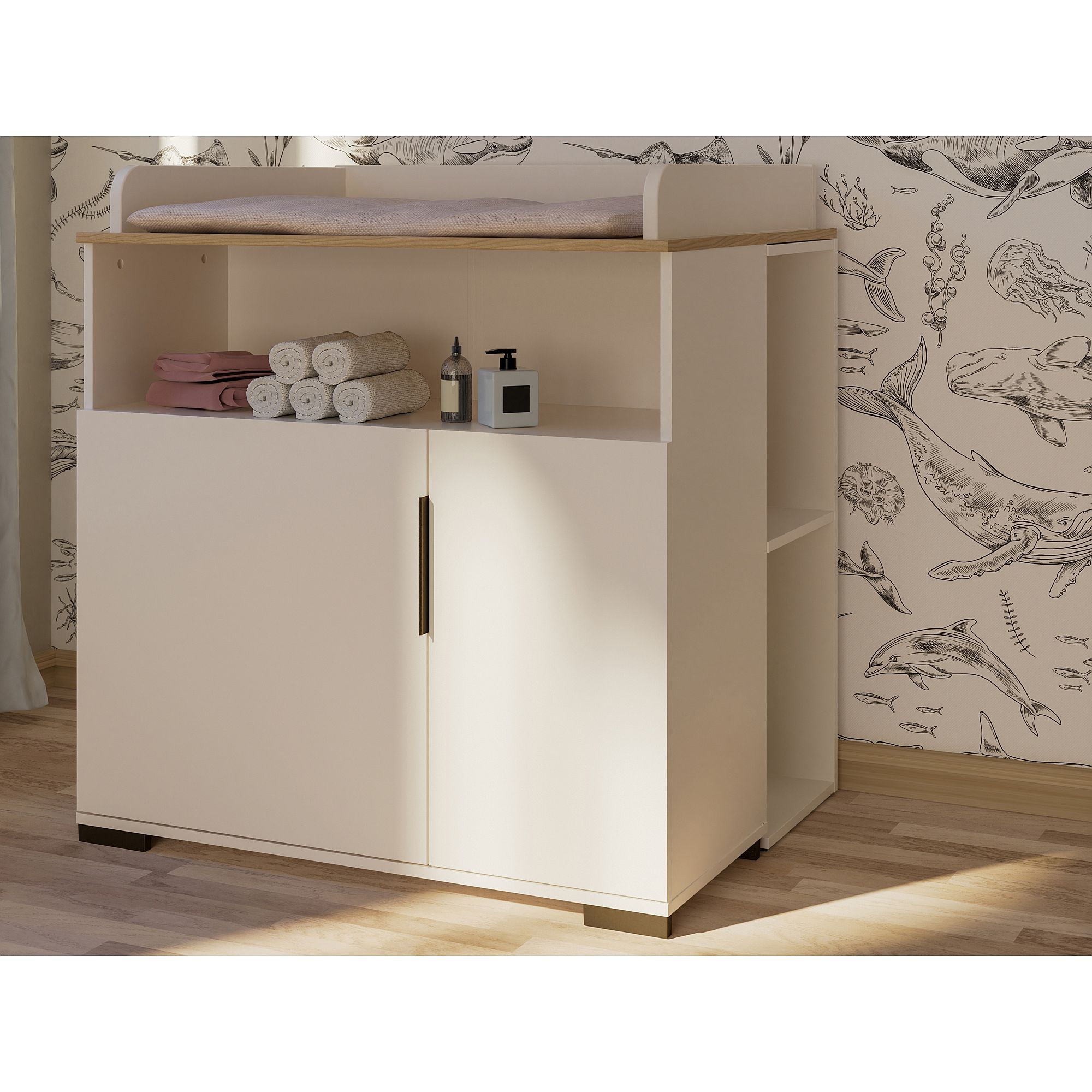 White changing table with towels and baby items, set against whale wallpaper.