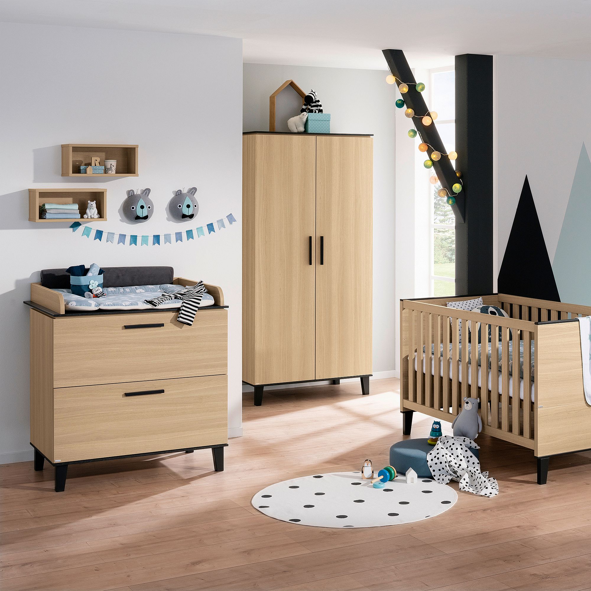 Modernes Kinderzimmer mit hellen Holzmöbeln, einem Kinderbett, einer Kommode und einer verspielten Einrichtung.