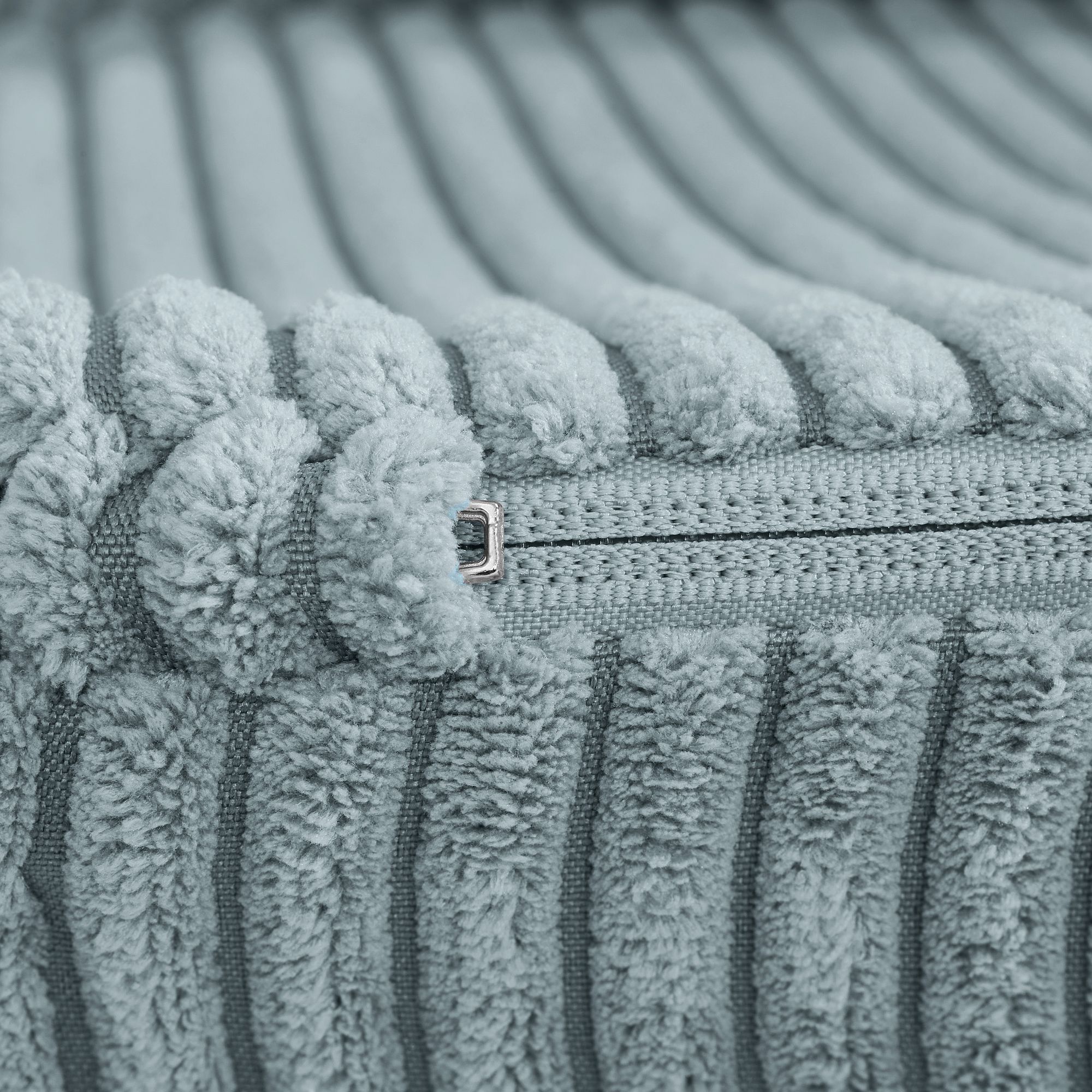 Nahaufnahme eines blauen, strukturierten Stoffes mit sichtbarem Reißverschluss.