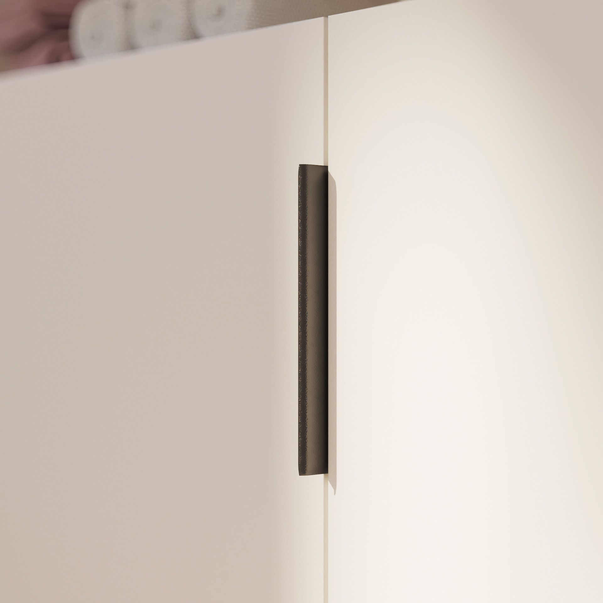 Nahaufnahme einer minimalistischen weißen Schranktür mit einem schlanken vertikalen Griff.