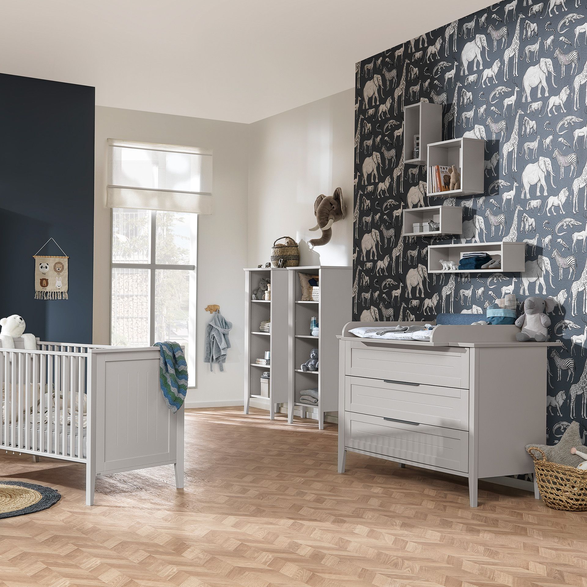 Modern nursery with animal wallpaper, crib, changing table, and shelves.