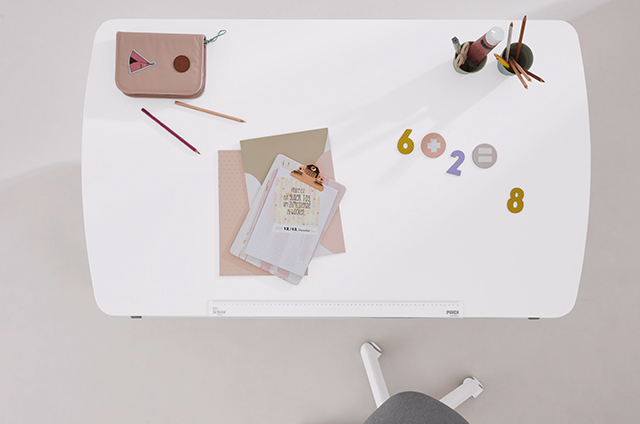A white desk with stationery, notebooks, pencils, a pouch, and cut-out numbers and symbols arranged neatly on top.