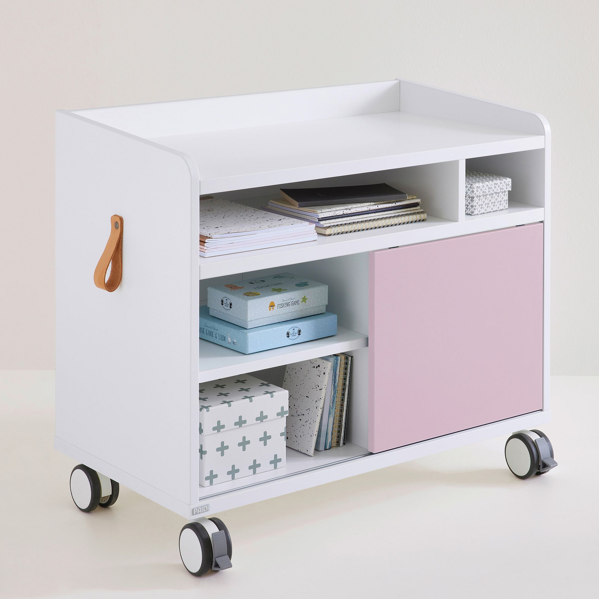 Weißer rollender Aufbewahrungswagen mit Regalen, rosa Tür, Büchern und Kisten darauf.
