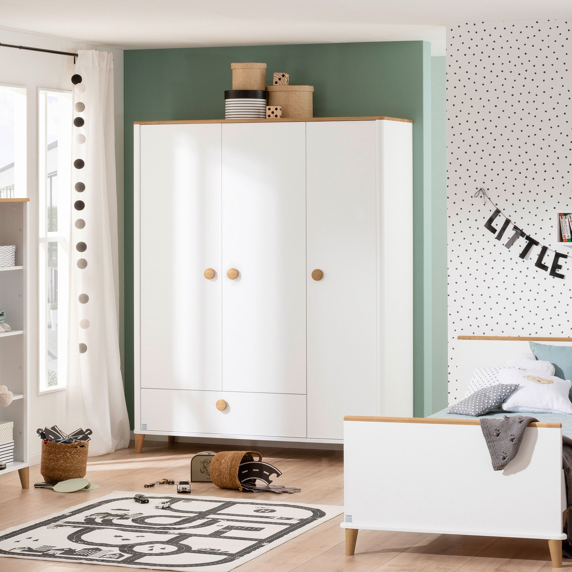 Drehtürenschrank Lotte & Fynn - Steiff by PAIDI 3 Türen, 1 Schublade Modern kids’ bedroom with white furniture, toys, and polka dot wall decor.