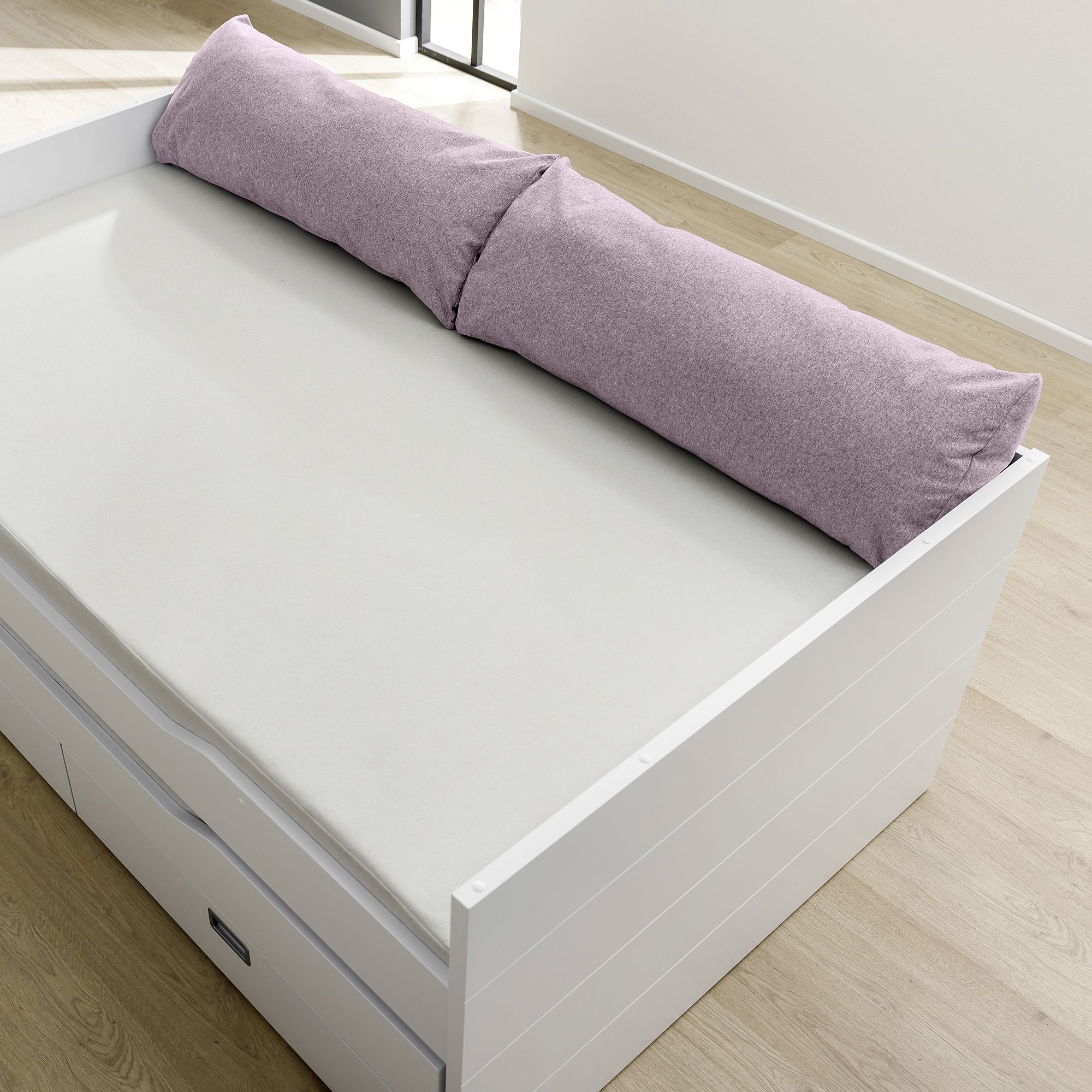 White daybed with a light purple bolster pillow and storage drawers underneath.