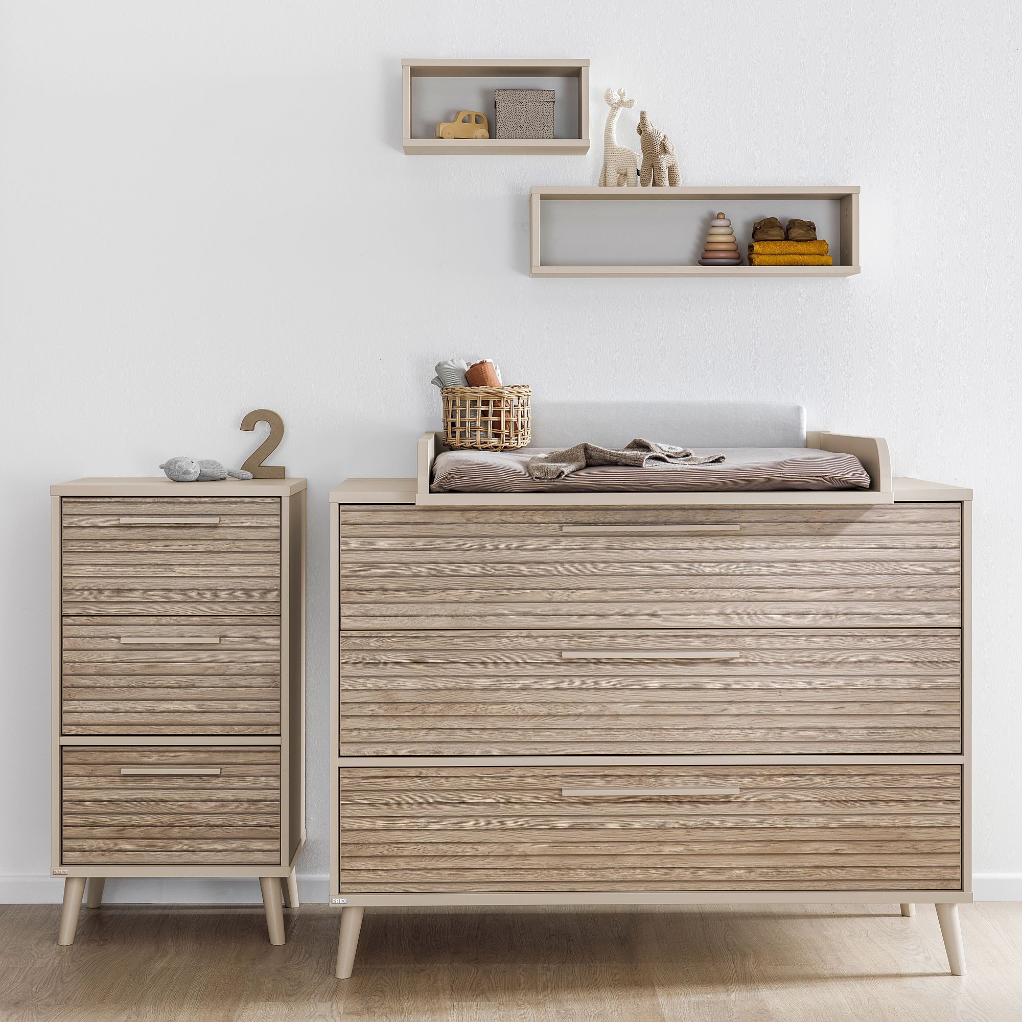 Wandregal  Wandbox  rechteckig  in Cashmere-Beige Wickeltisch und Kommode aus hellem Holz mit Spielzeug und Dekoration in den Regalen darüber.