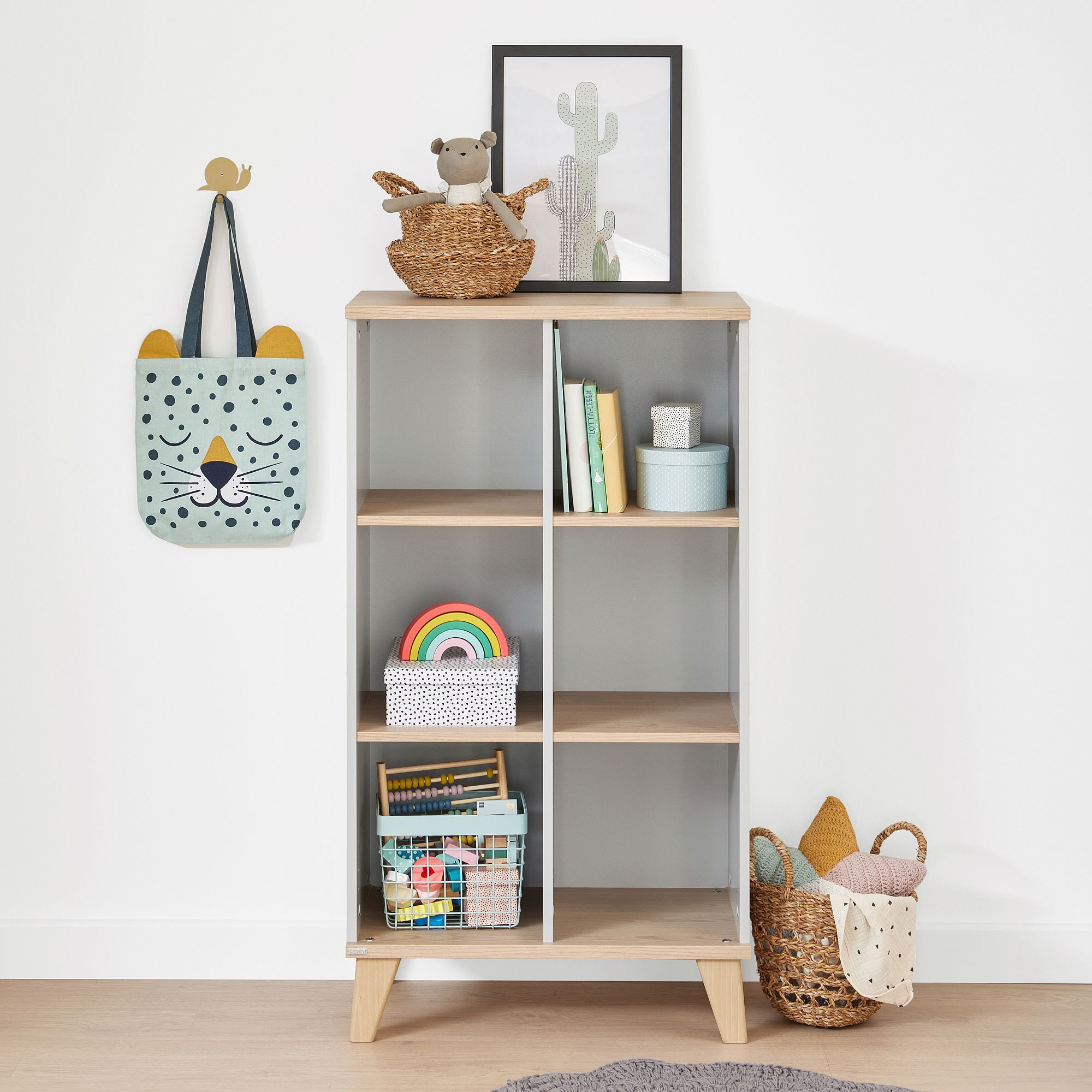 Childrens bookshelf with toys, books, baskets, and cute wall decor nearby.