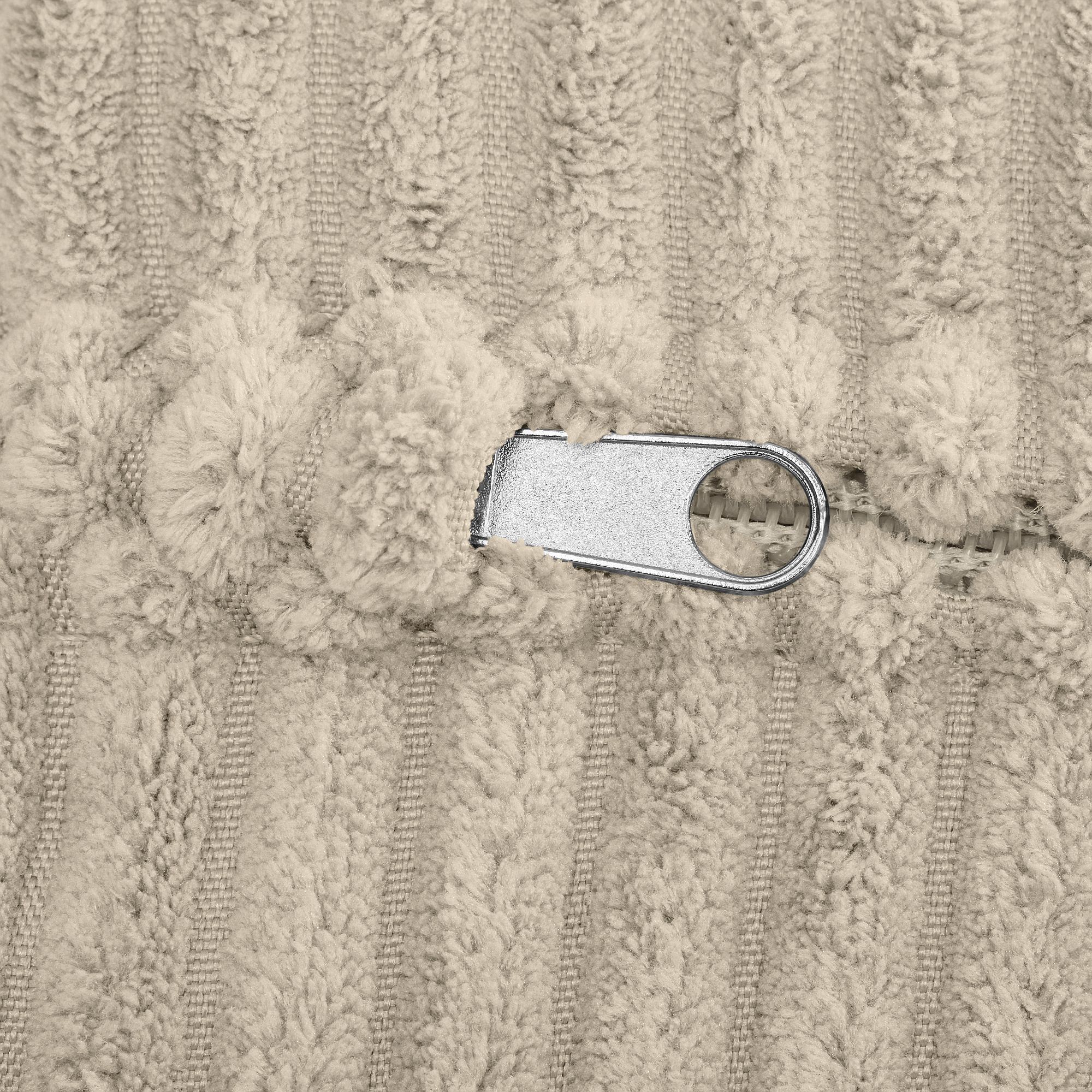 Nahaufnahme eines Metallreißverschlusses auf strukturiertem beigem Stoff.