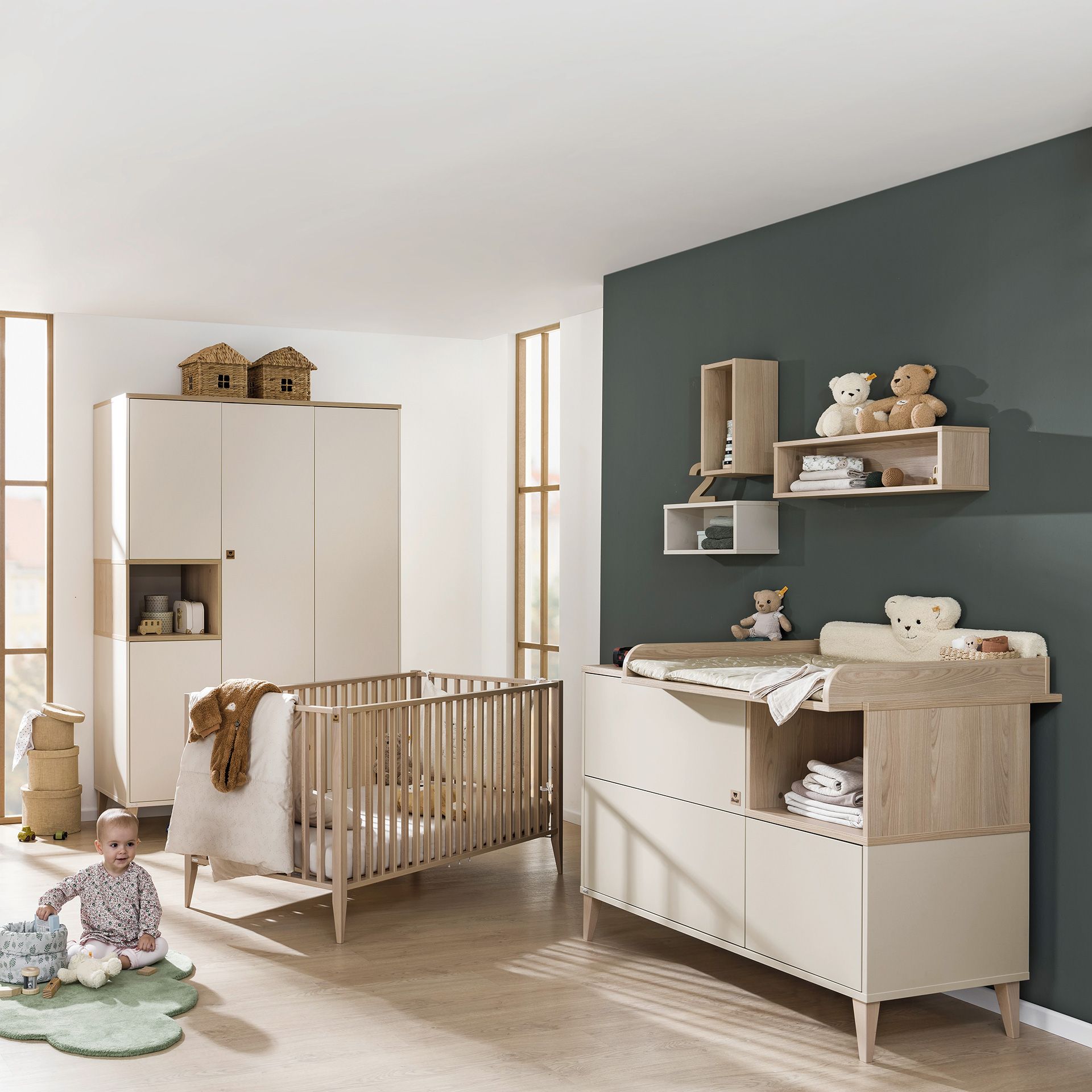 Modernes Kinderzimmer mit Kinderbett, Wickeltisch, Regalen und einem Baby, das auf dem Boden sitzt.