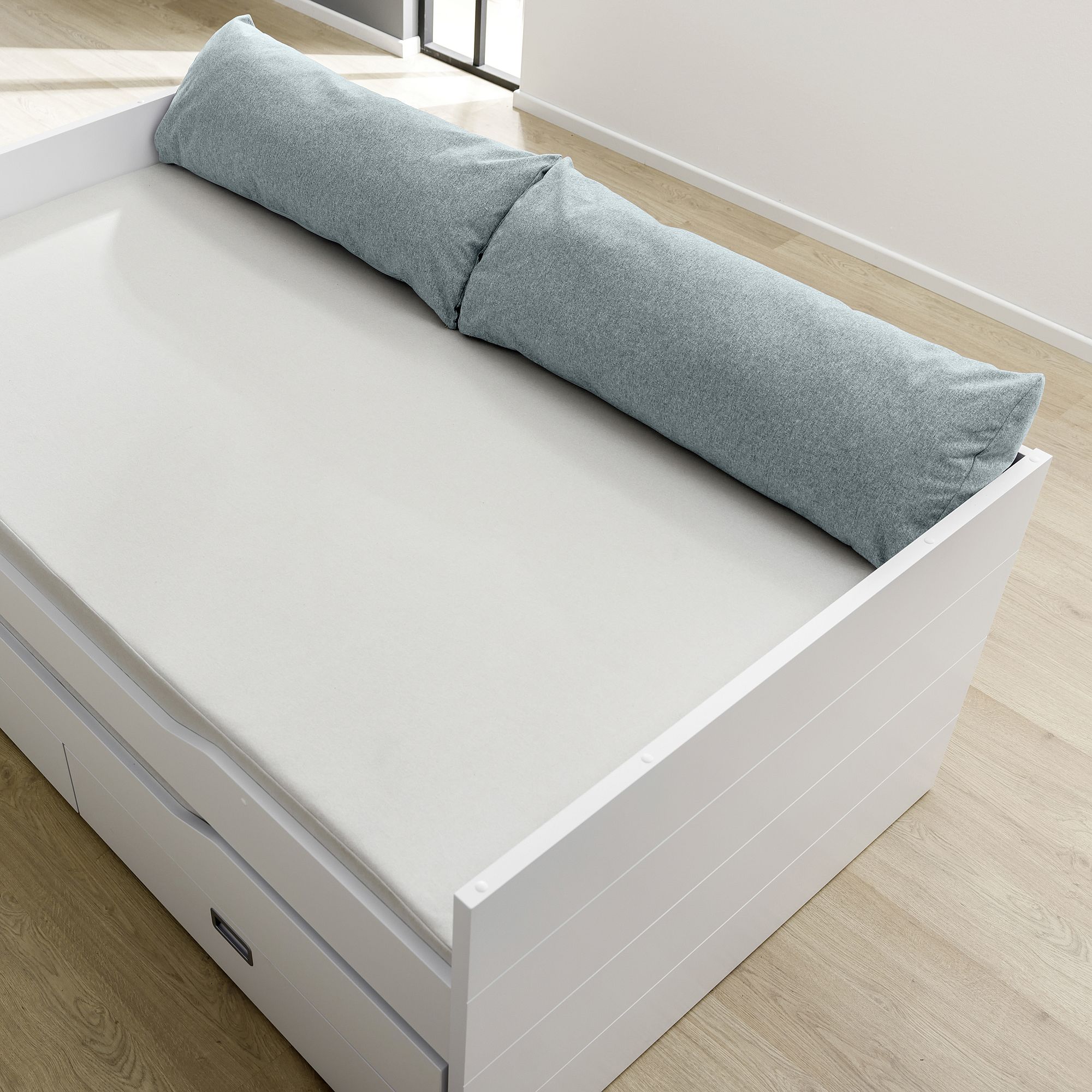 A white daybed with a light gray cushion and storage drawers underneath.