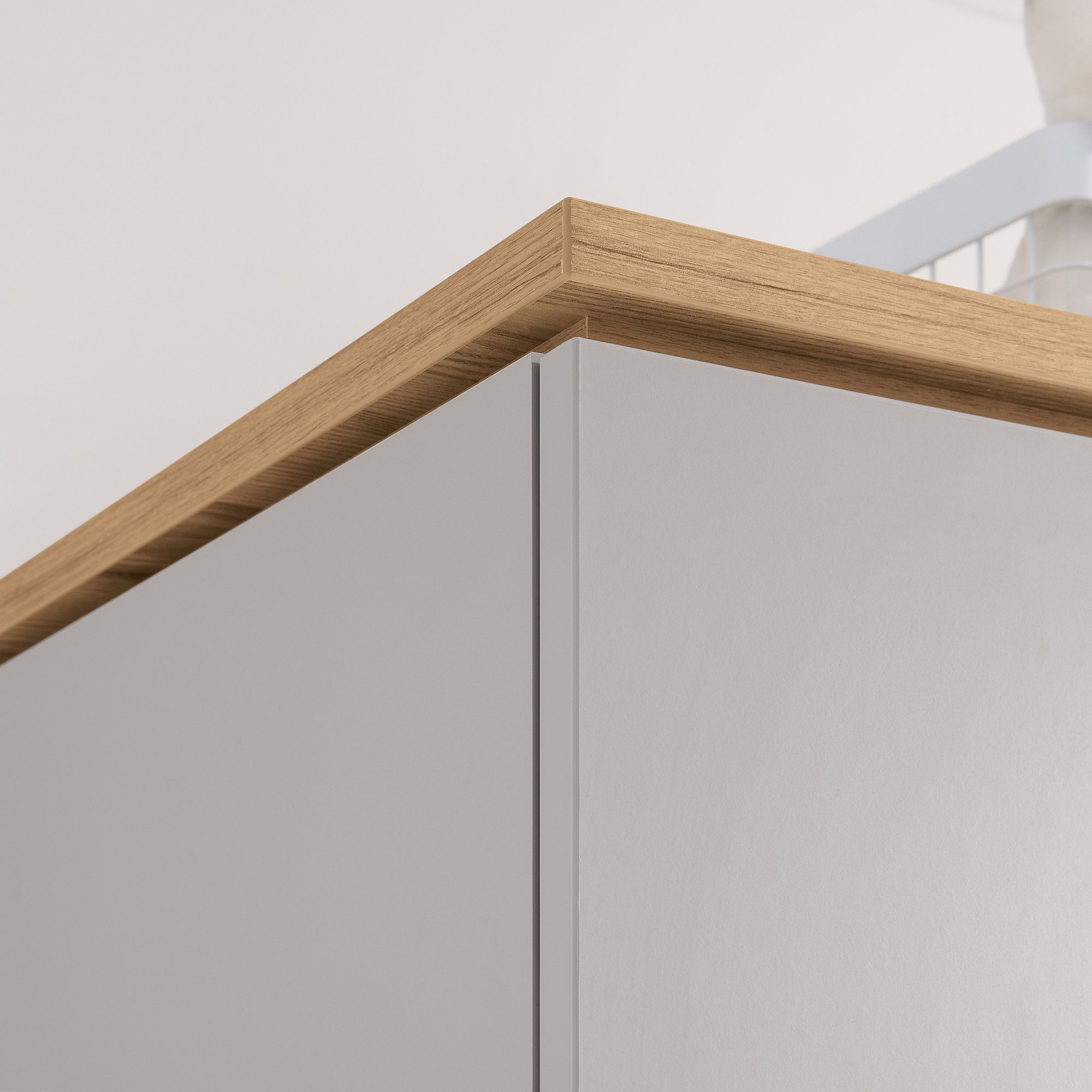 Nahaufnahme einer Schrankecke mit einer Holzplatte und einer hellgrauen Seitenwand.