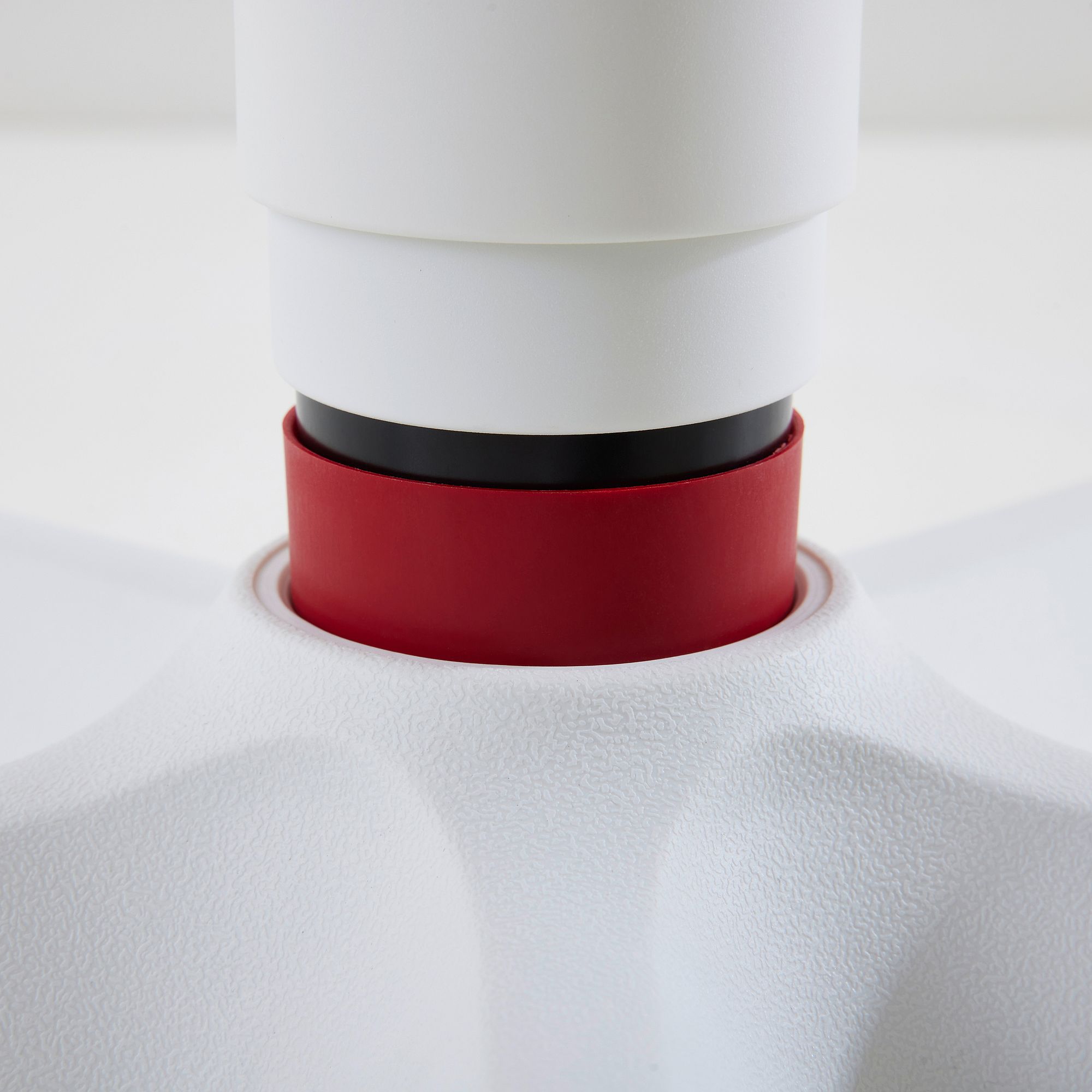 Drehstuhl Jooki S ergonomisch mitwachsend im Mikrofaserbezug  Steingrau Nahaufnahme eines weißen Objekts mit einem roten und schwarzen Ring in der Mitte.