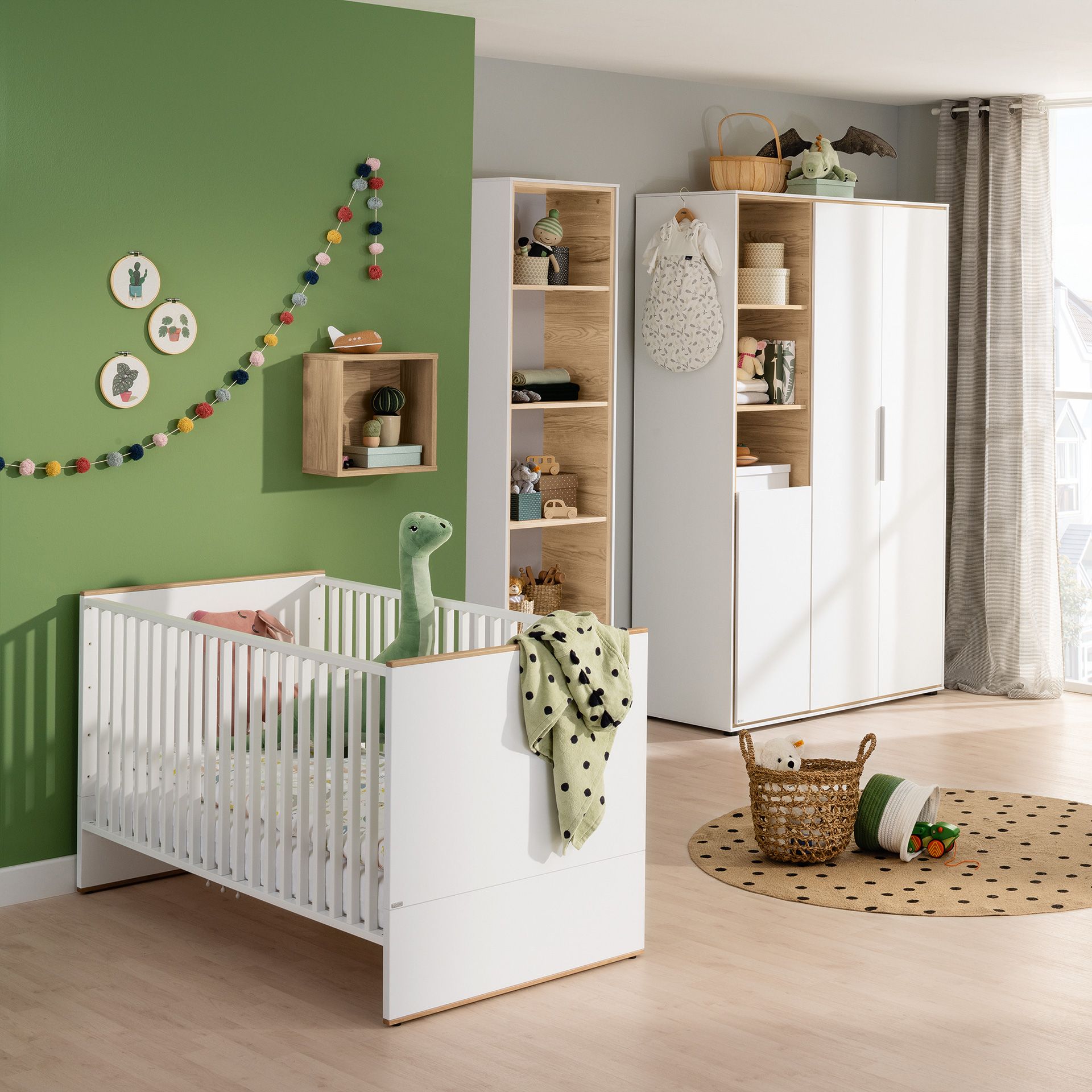 Modernes Kinderzimmer mit einem weißen Kinderbett, einer grünen Wand, Regalen und Dekorationen mit Tiermotiven.