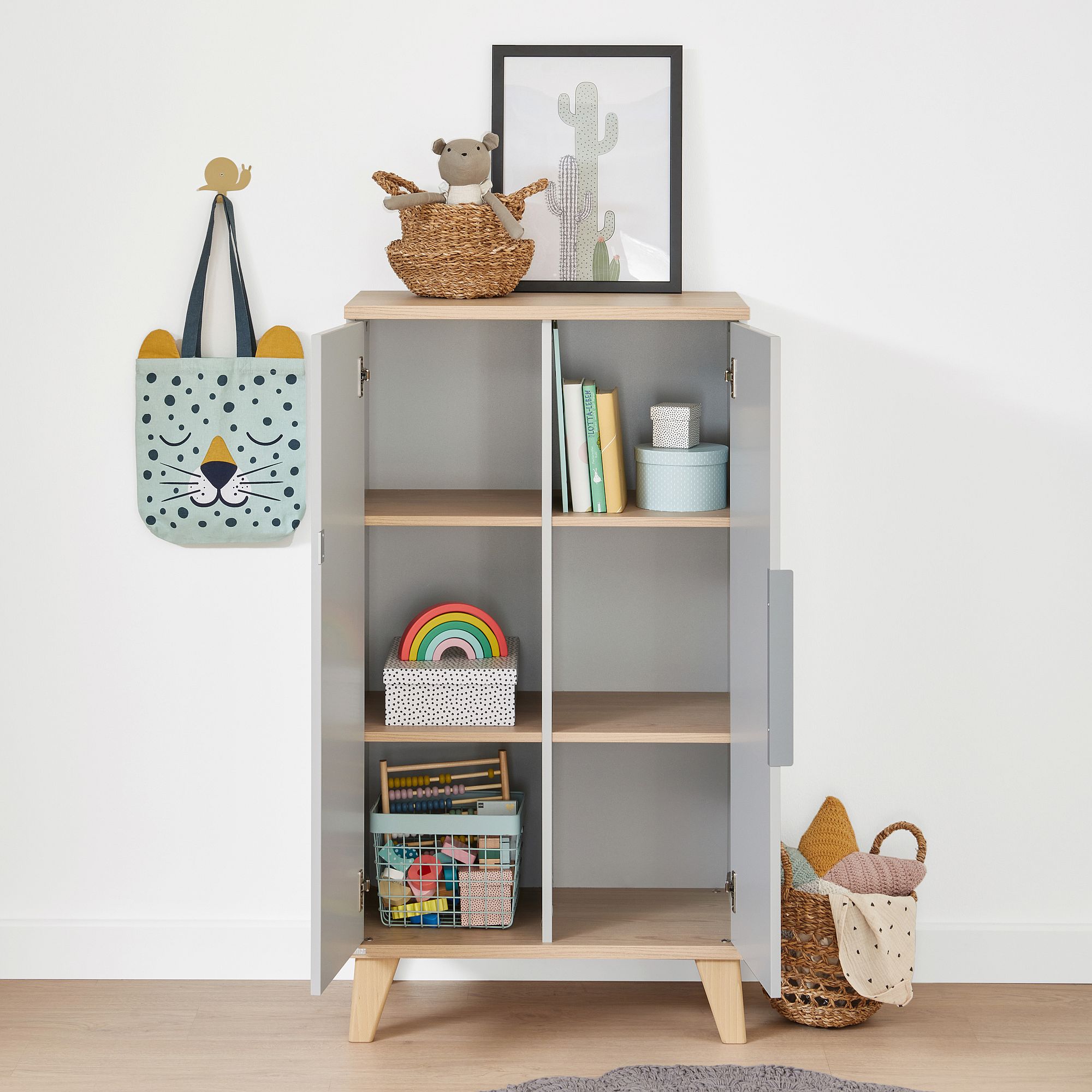 Standregal Fiene mit 2 Türen Grauer Schrank mit offenen Türen, Kinderspielzeug, Bücher und Körbe innen und oben.