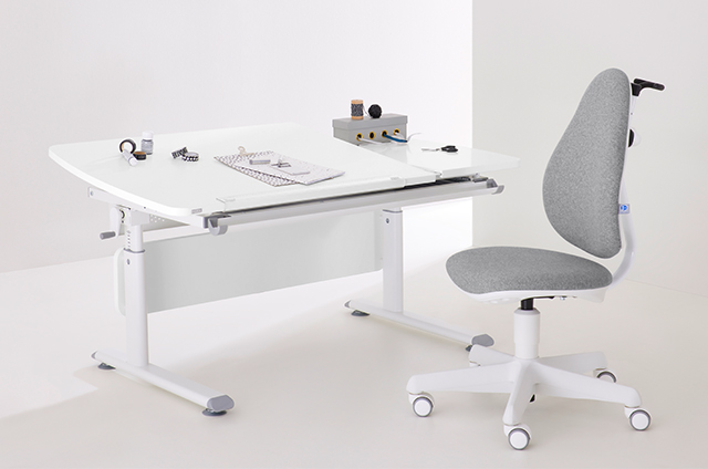 A modern white desk with a grey ergonomic chair, stationery, and a notebook on the tabletop in a minimal workspace.