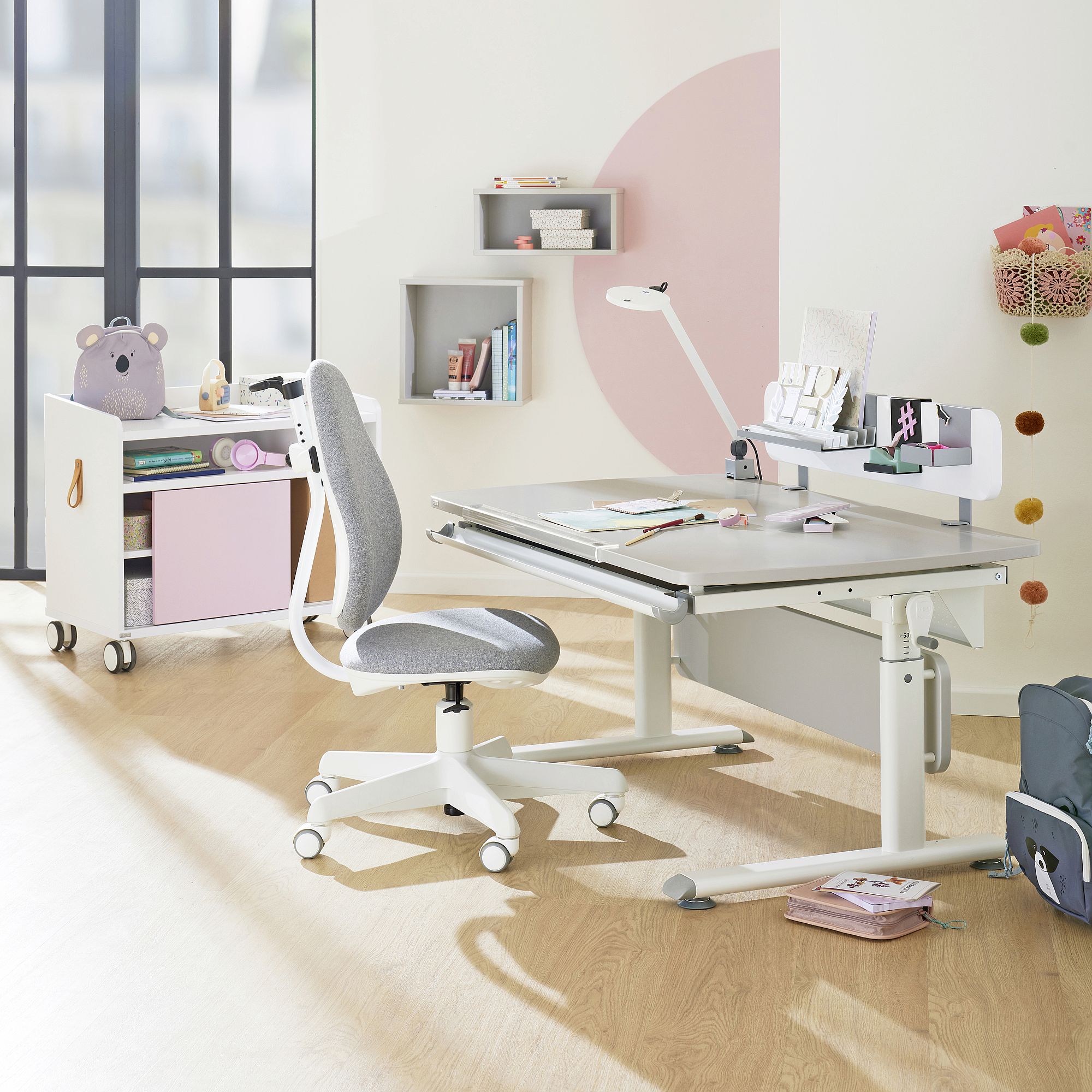 Schülerschreibtisch Diego Curved 120 x 70 cm in Kieselgrau Moderner Arbeitsbereich für Kinder mit verstellbarem Schreibtisch, Stuhl und Regalen in einem hellen Raum.