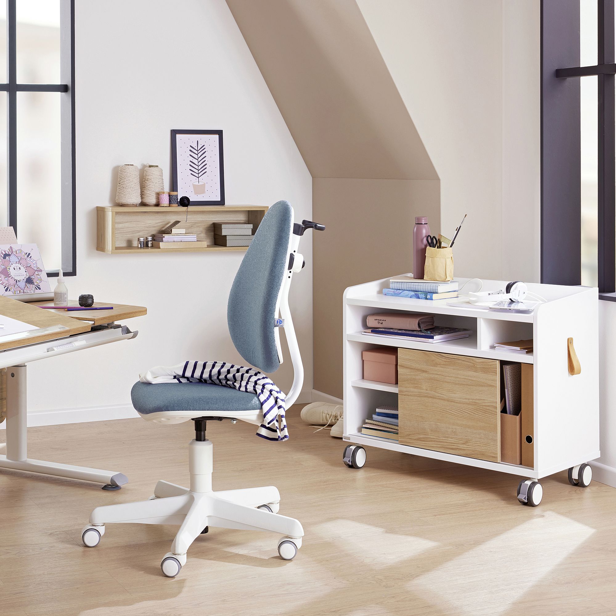 Modern home office with desk, ergonomic chair, and rolling storage cart.