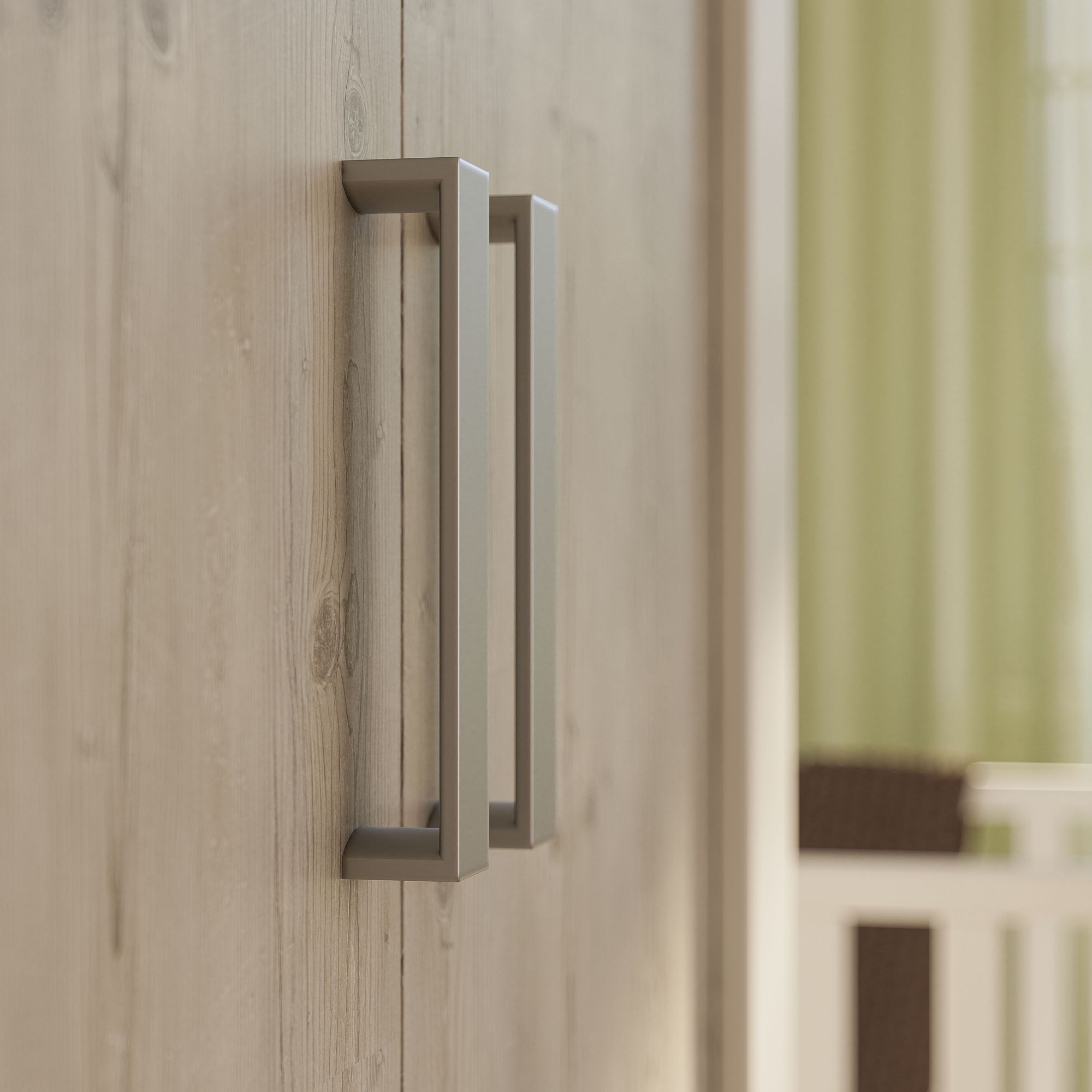 Nahaufnahme von modernen silbernen Griffen an einer hellen Holztür.