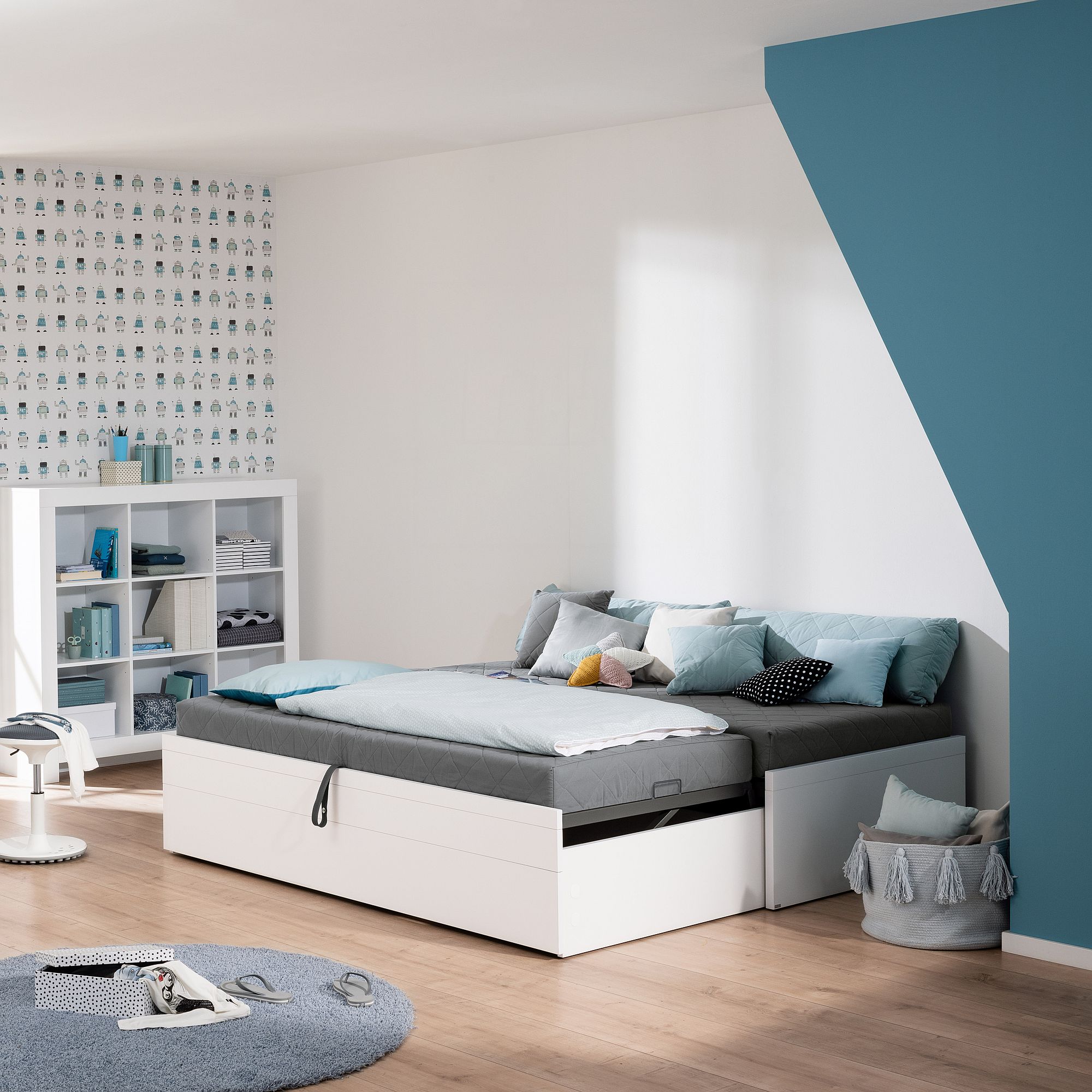 Modernes Schlafzimmer mit einem ausziehbaren Bett, blauen Akzenten und dekorativen Kissen.