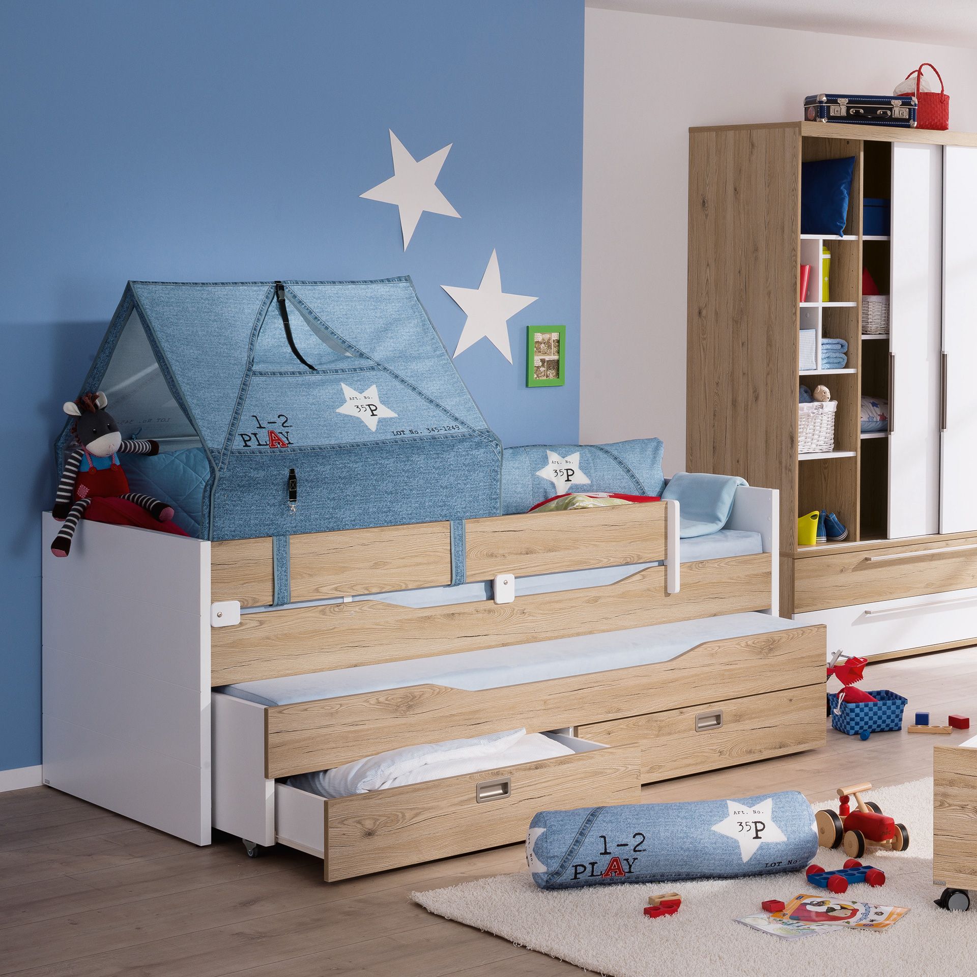 Kinderzimmer mit einem Zeltbett, blauer Wand, Spielzeug und Holzmöbeln.