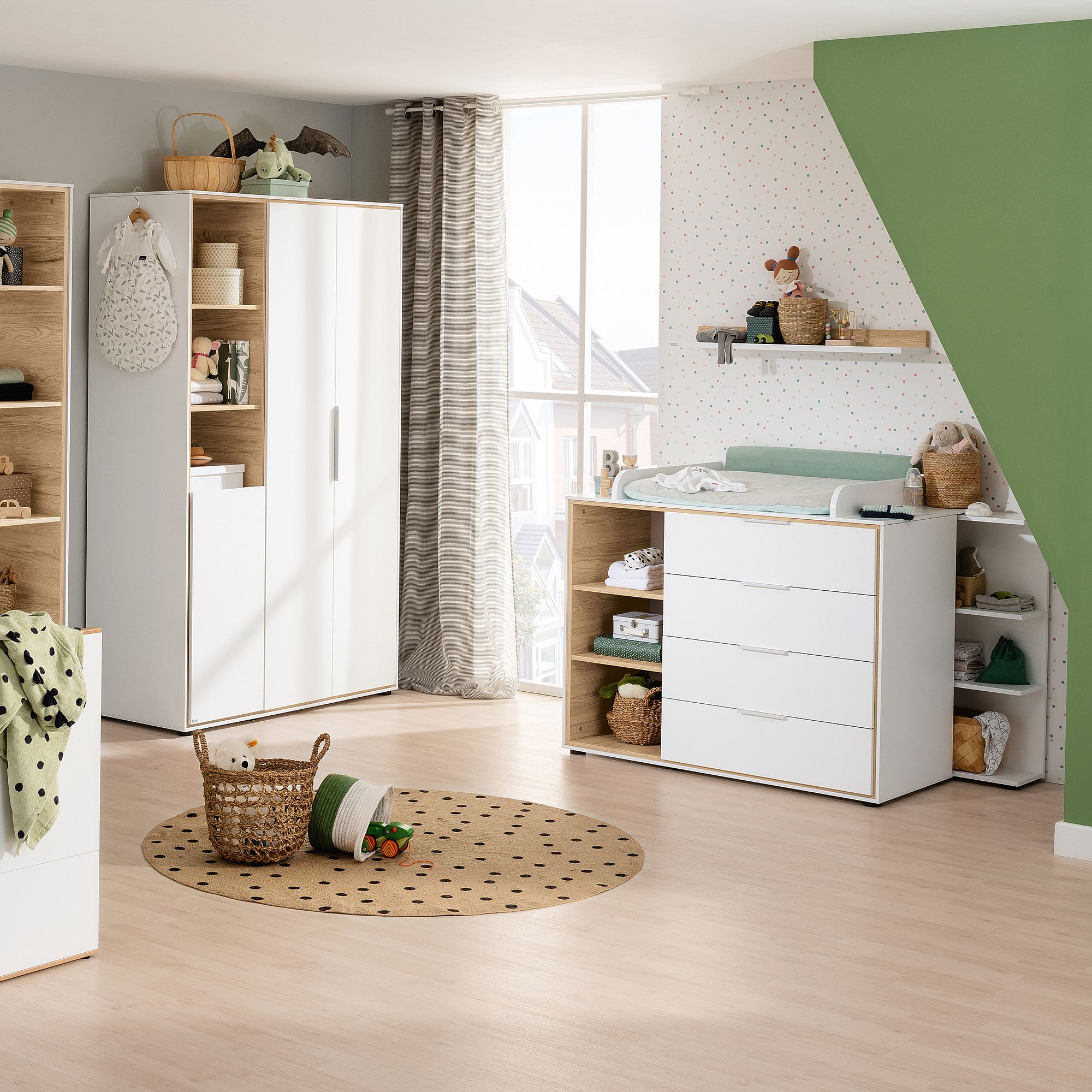 Modernes Kinderzimmer mit weißen Möbeln, einem gepunkteten Teppich und einer grünen Akzentwand.