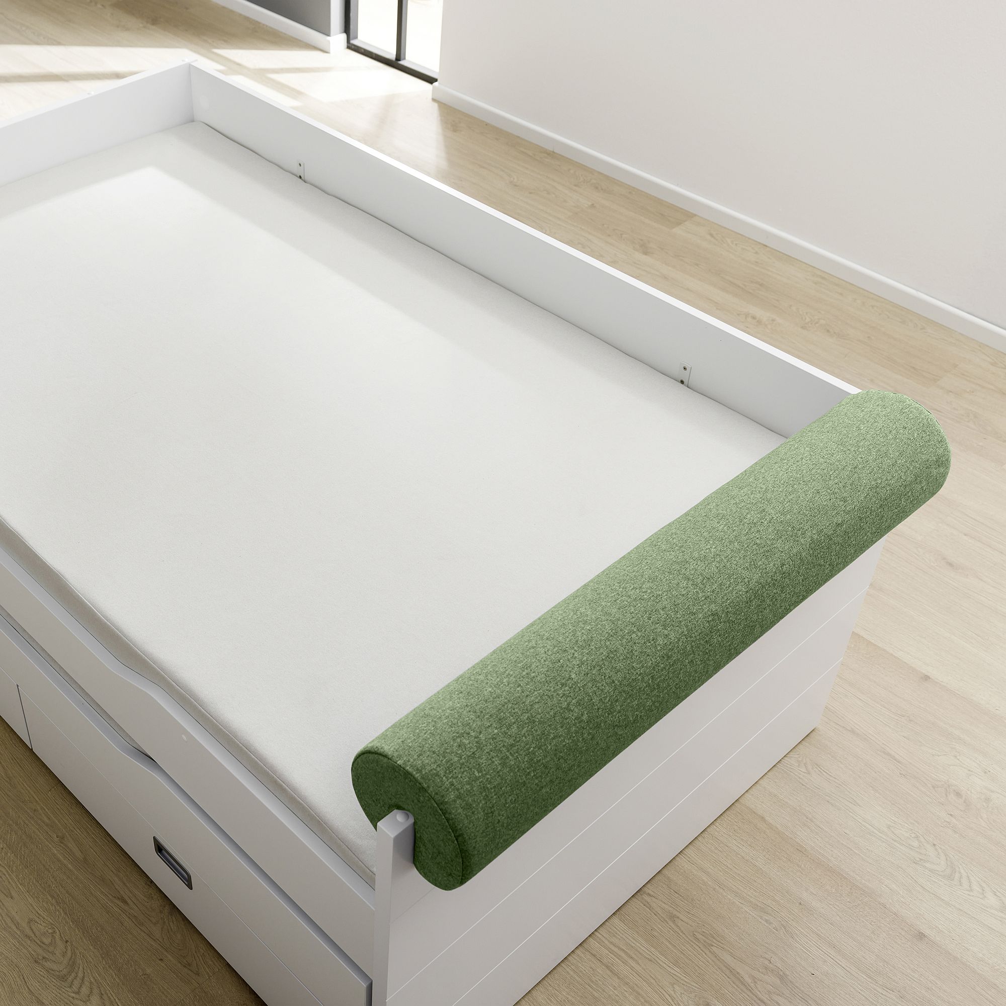 White bed with a green cylindrical cushion on the side, in a bright room.