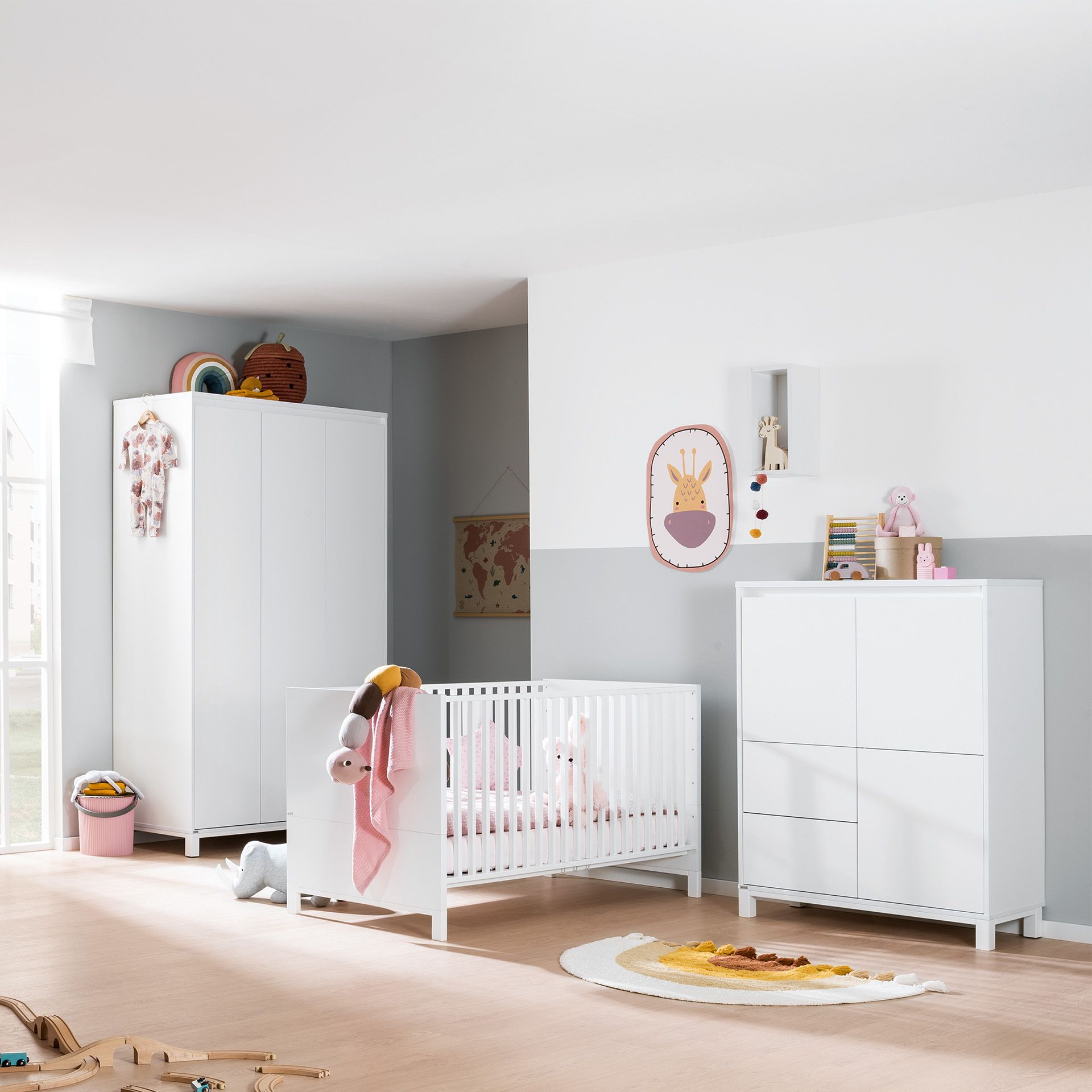 Modernes Kinderzimmer mit weißen Möbeln, einem Kinderbett, Spielzeug und Dekorationen in Pastelltönen.
